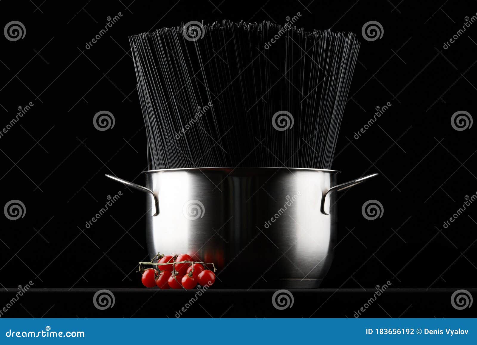 Black Spaghetti Pasta in a Saucepan with Fresh Tomatoes on a Black
