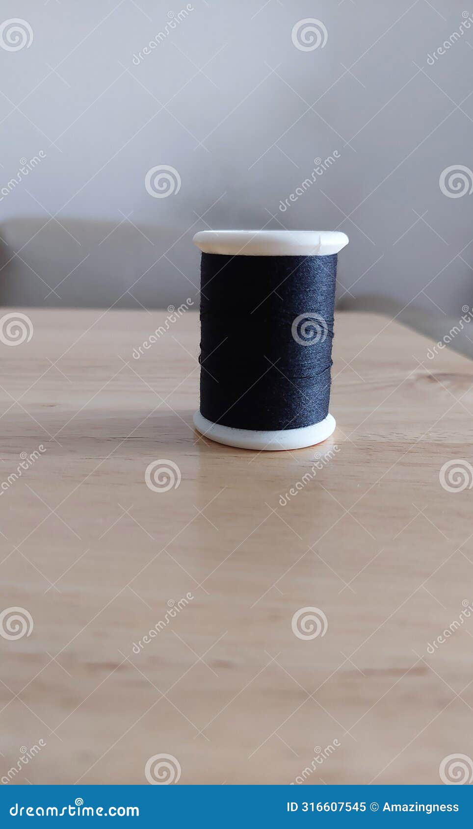 black spool of sewing thread on wooden table.