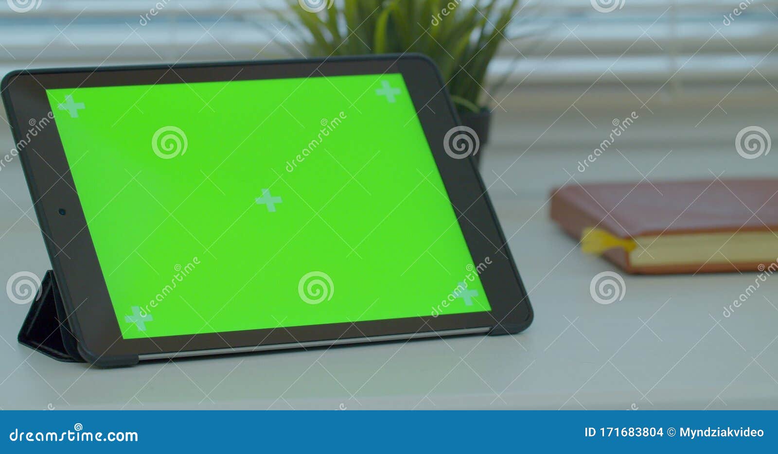 black tabletpc on a desk with green screen and book. close up 4k footage.