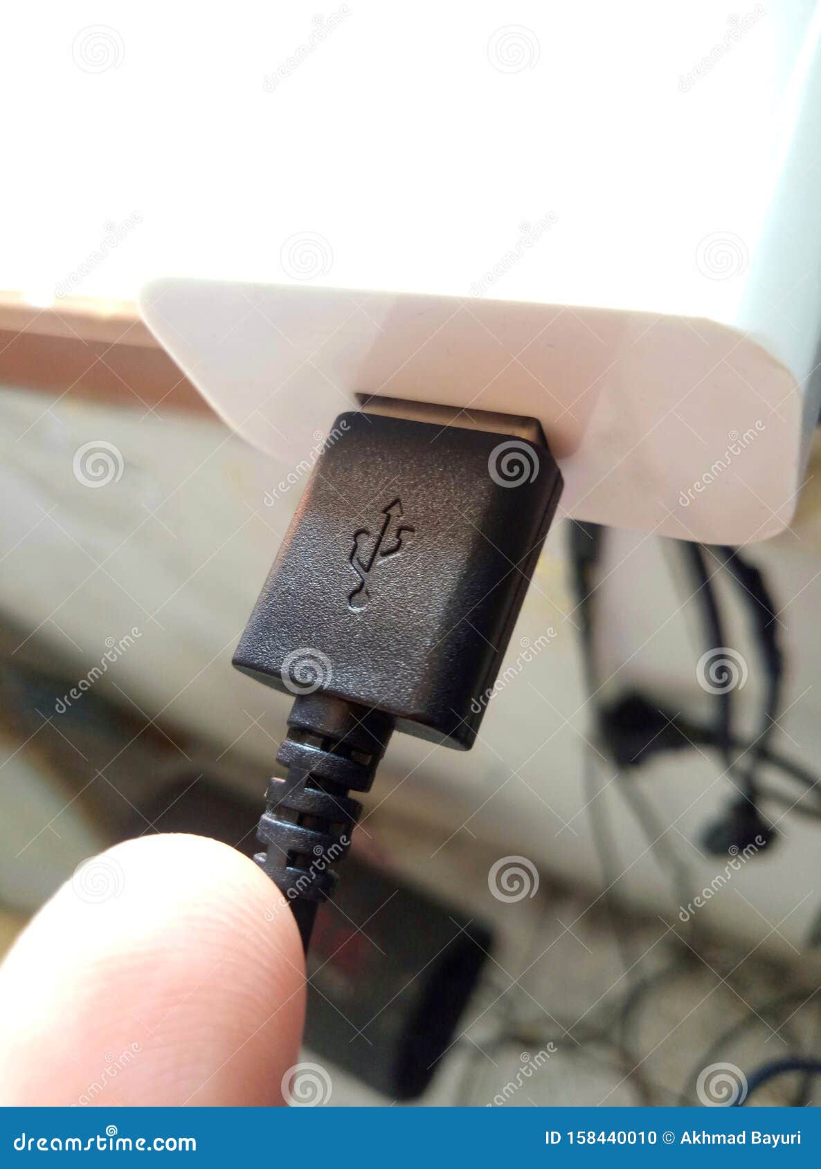 a black usb cable stuck to the adapter in a messy room