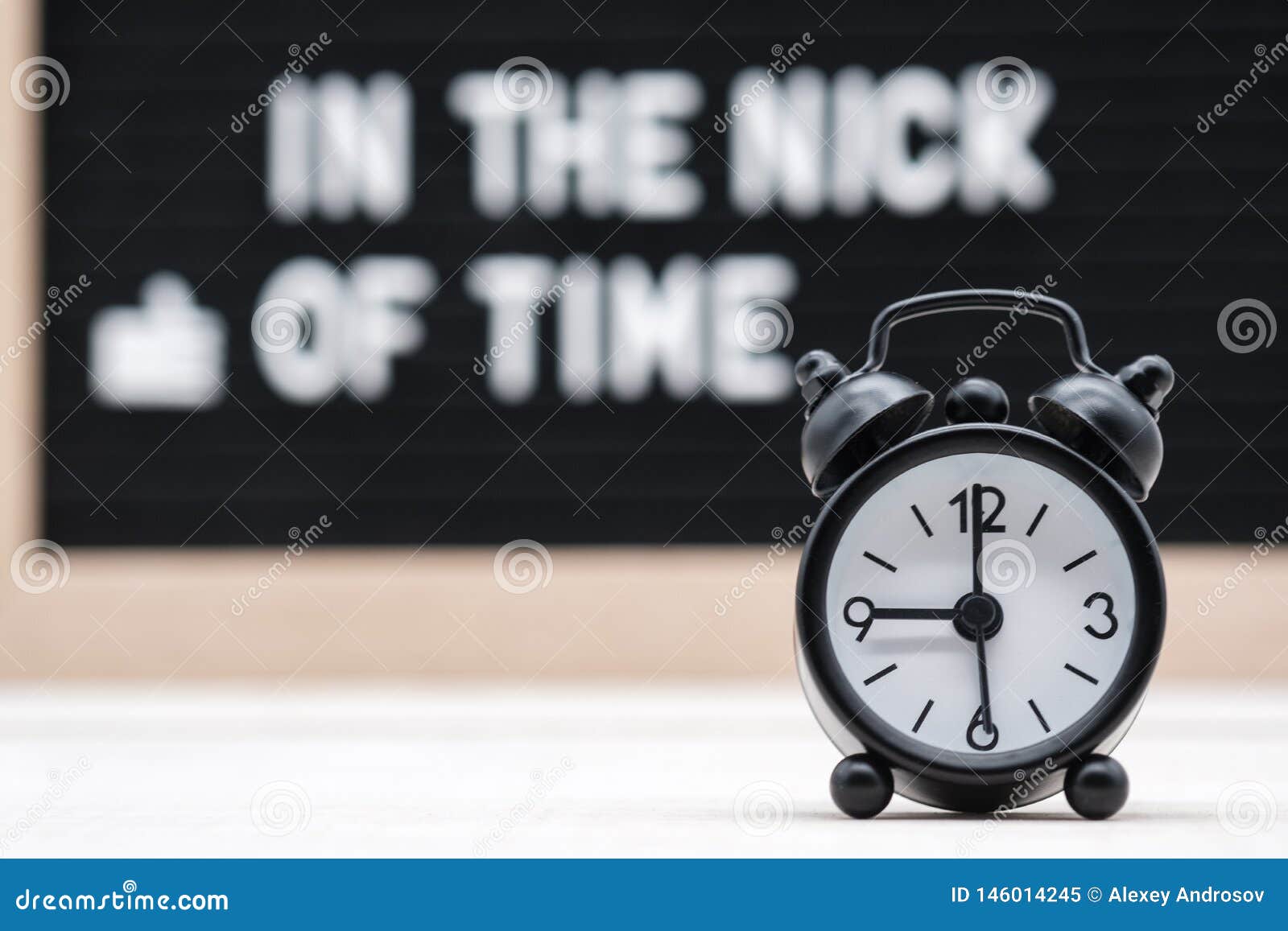 black vintage alarm clock on the background of signs with the inscription in the nick of time