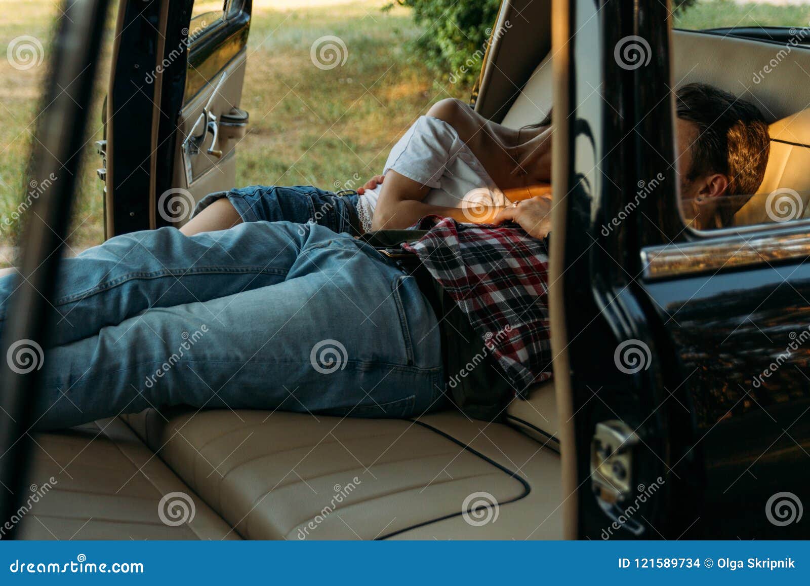 date in the car.people who are lying in the car and holding hands. look through the window in the car.side view.black watch on man