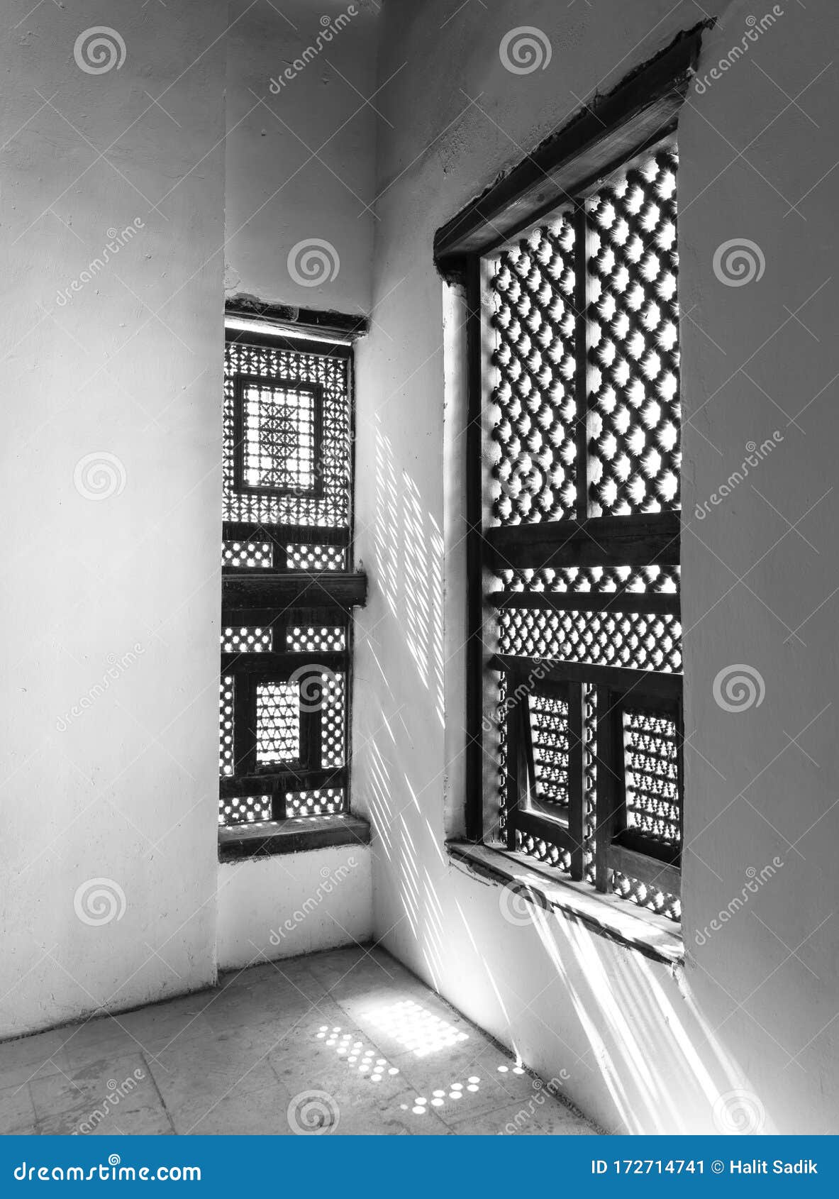 black and white of corner of two interleaved wooden ornate windows - mashrabiya - in stone wall