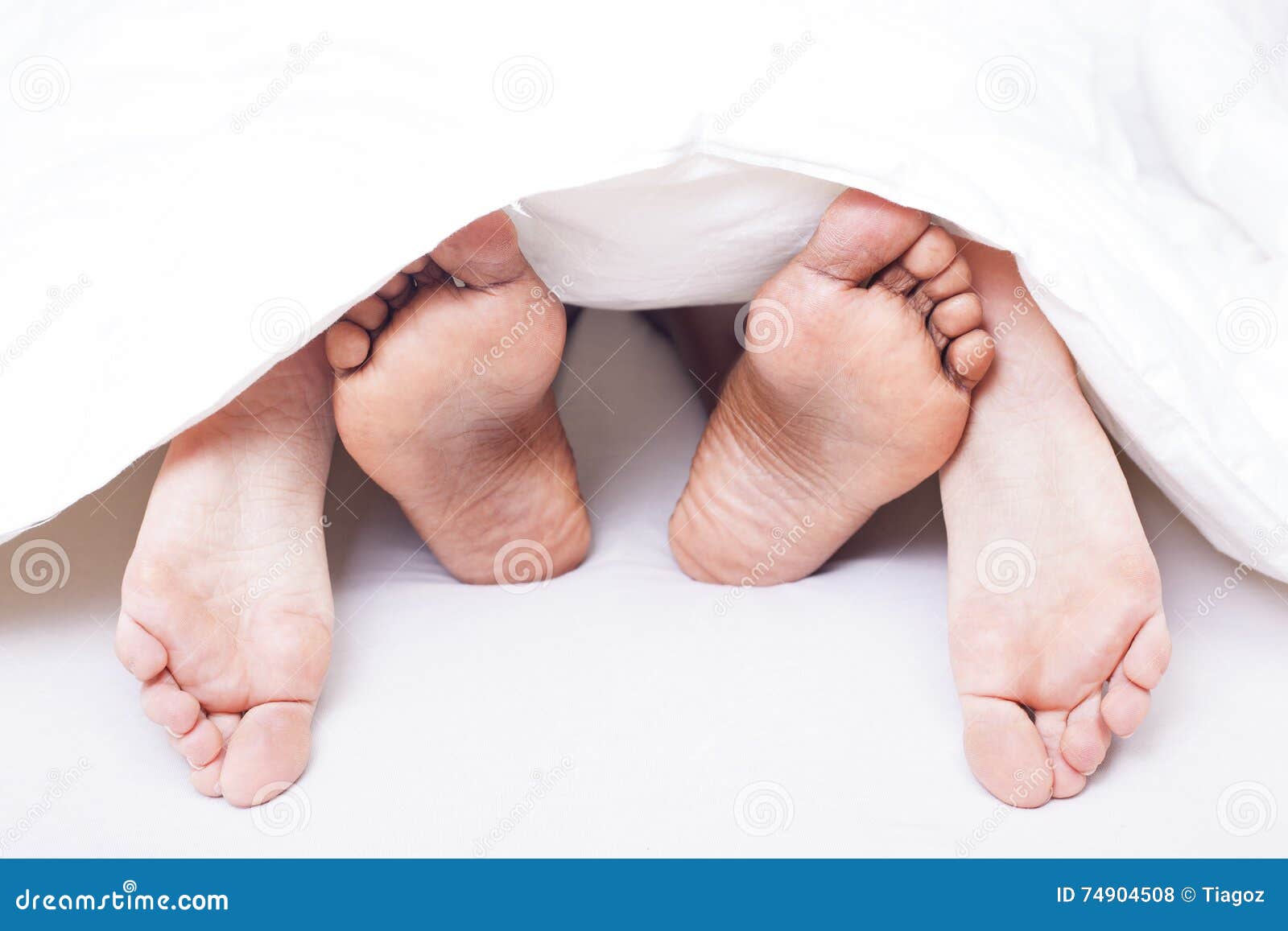 Black And White Feet Of Interracial Couple In Bed Stock