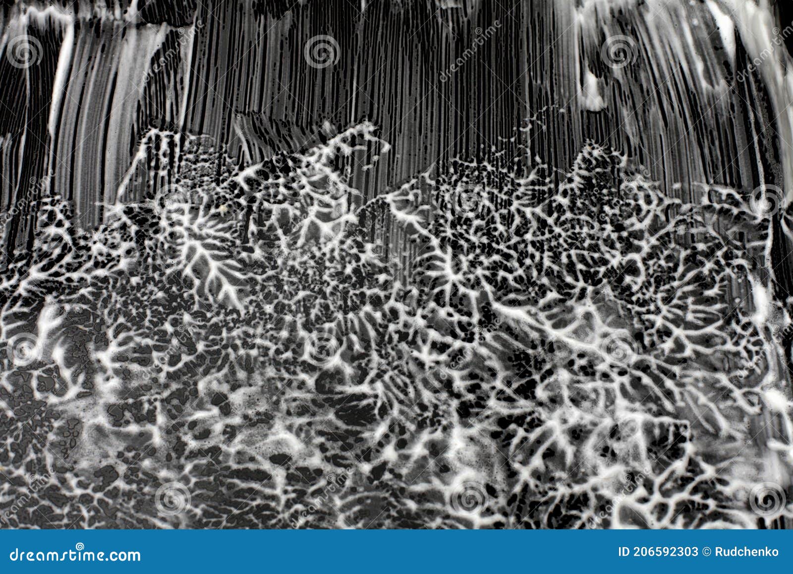 black and white foamy wawe stains on a smooth black surface. abstract texture background