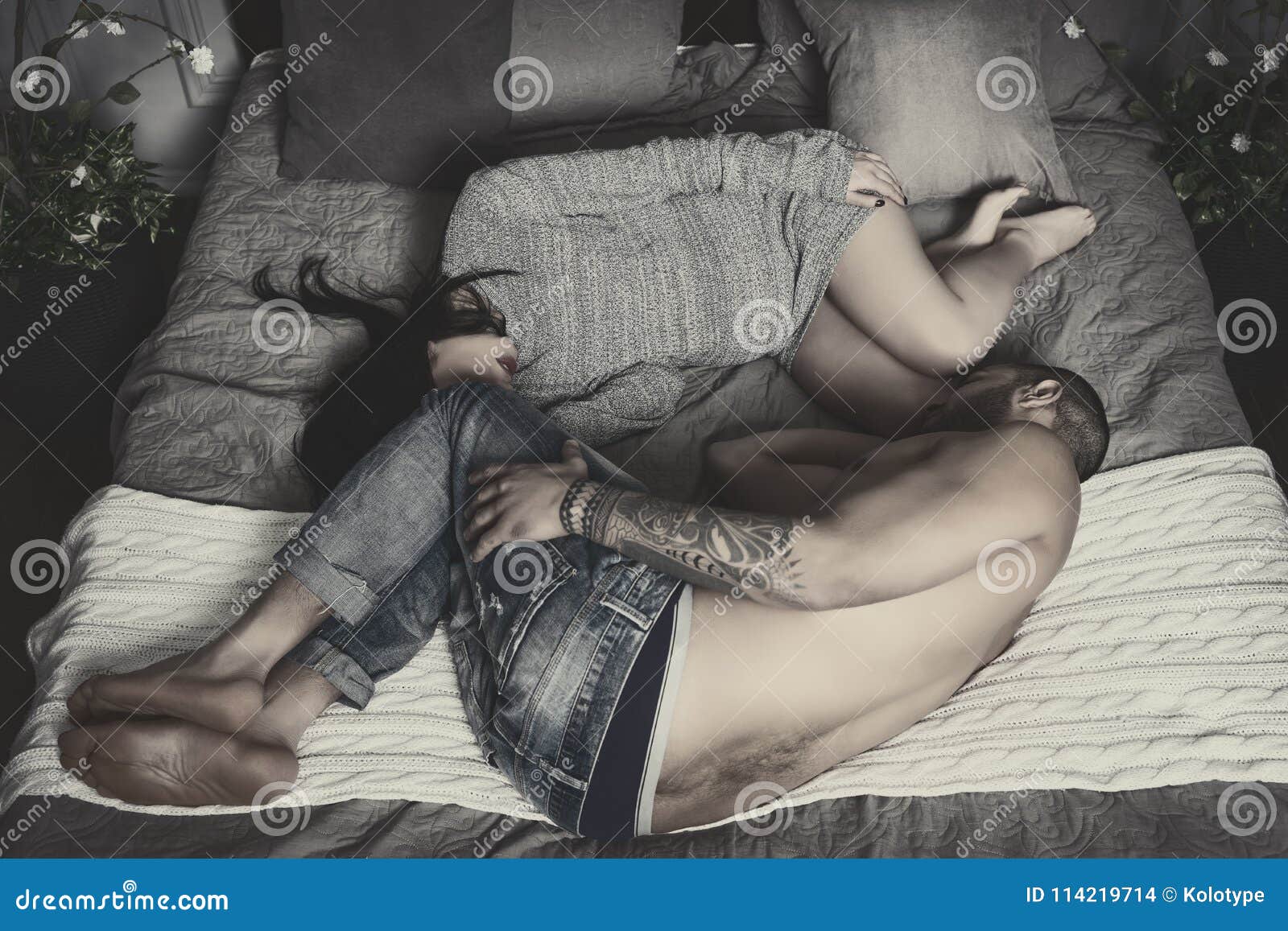 Black and White Photo of Couple of Man with Bare Chest and Tattooed Hands and Brunette Pregnant Woman Lying in the Fetal Position Stock Photo picture pic