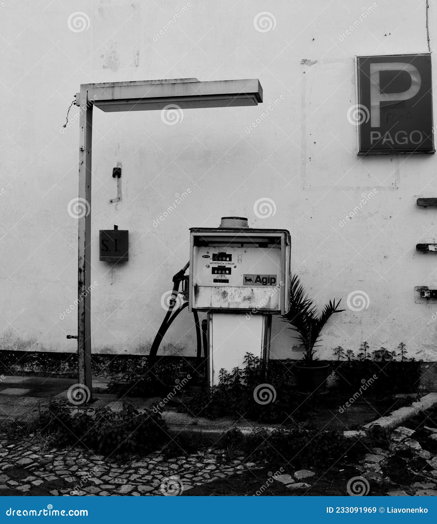 black and white photo. an old gas station in an abandoned parking lot.