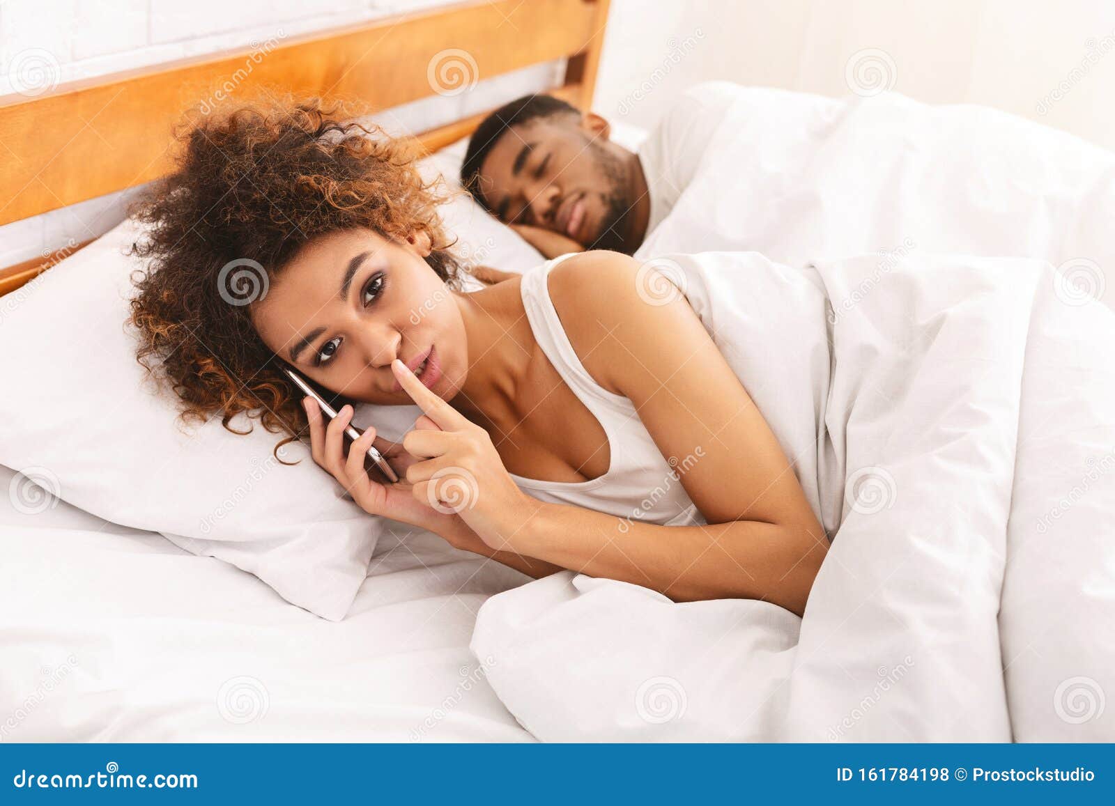 black wife cheater talking privately on cellphone in family bed