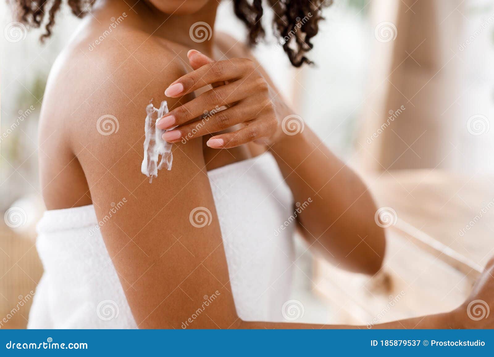 black woman applying moisturizing body lotion on skin after shower