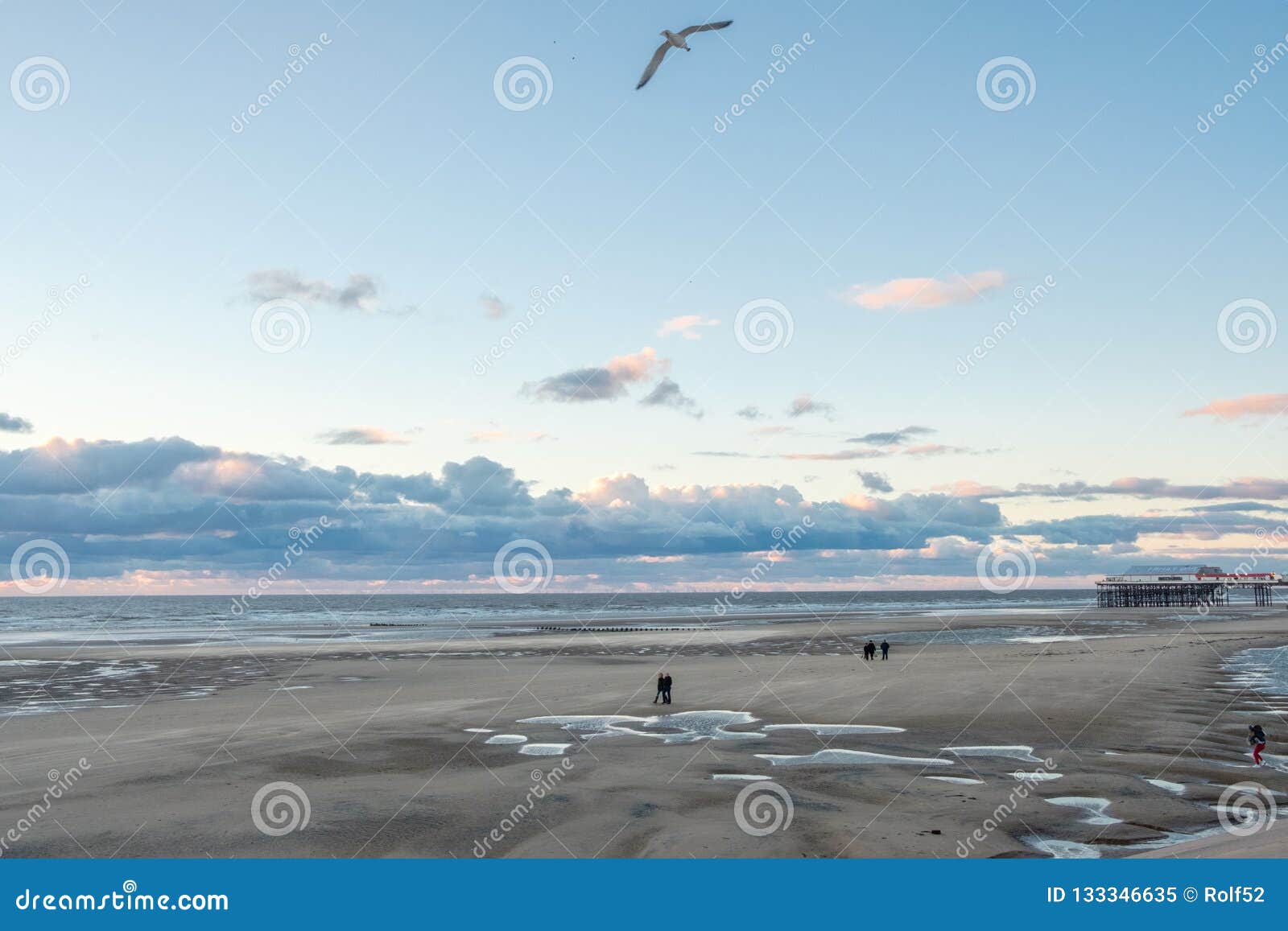 Blackpool Beach during fall. Unrecognizable tourists stroll on Blackpool Beach at sunset during an autumn weekend in late October 2018. Blackpool is one of Englands favorite seaside resorts.