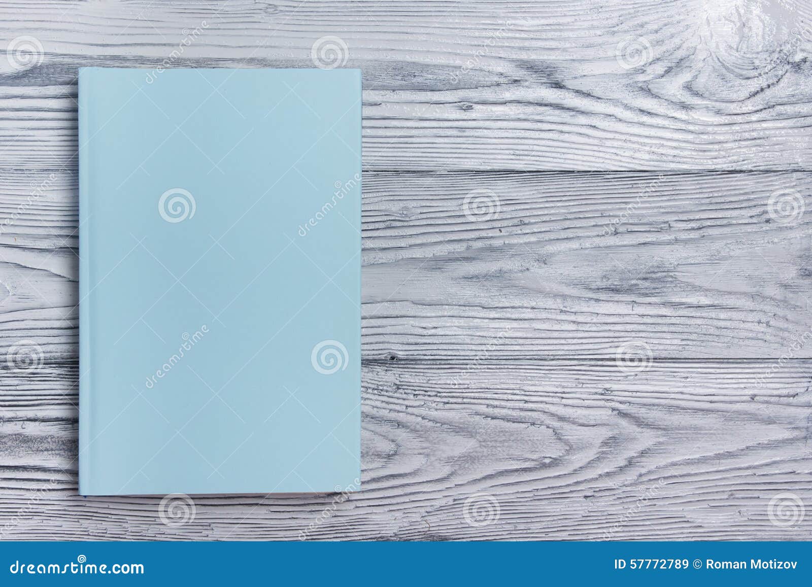 Blank book cover on textured wood background. Copy space.