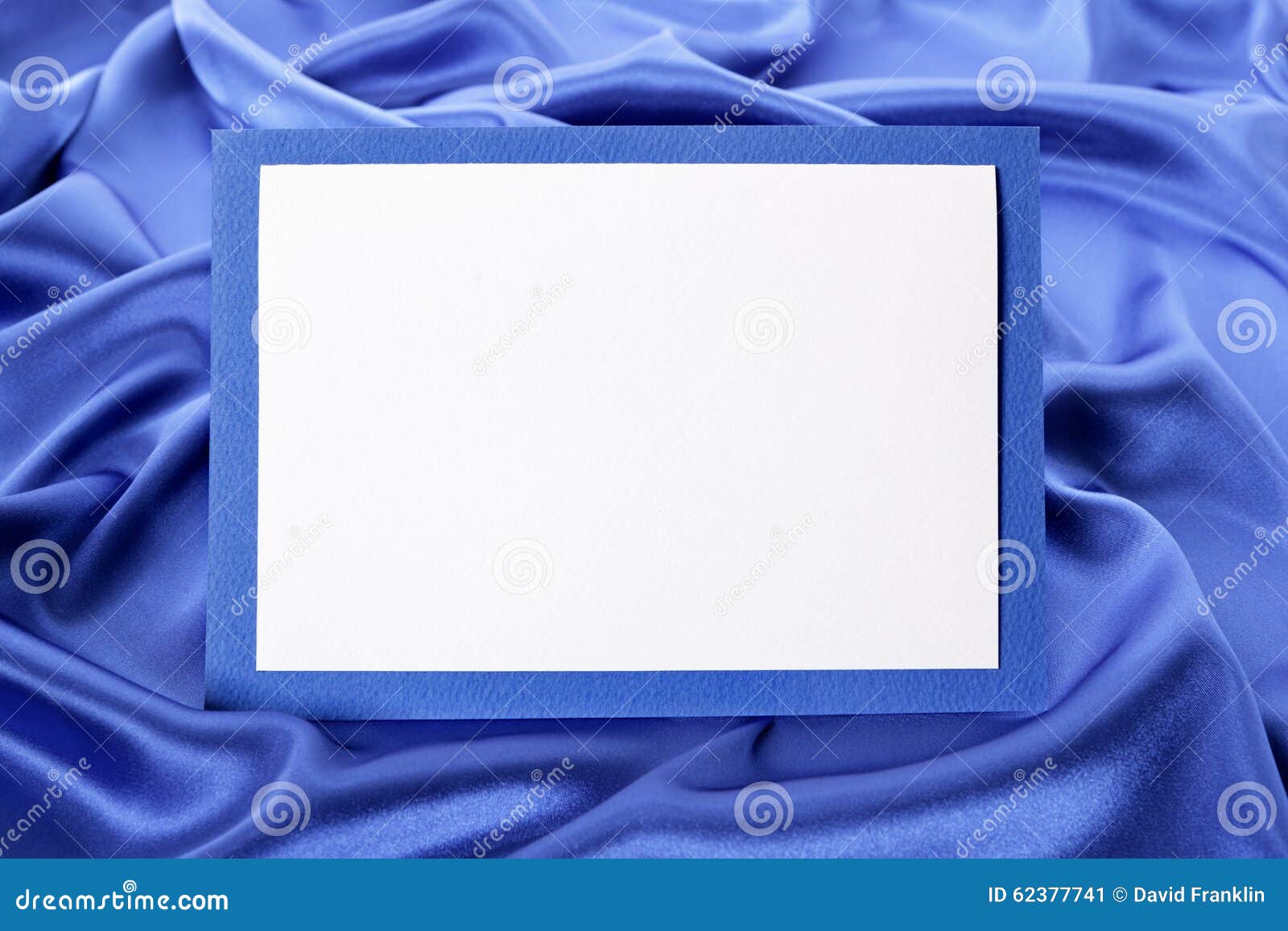 blank christmas or birthday greetings card or invitation with blue satin background, copy space