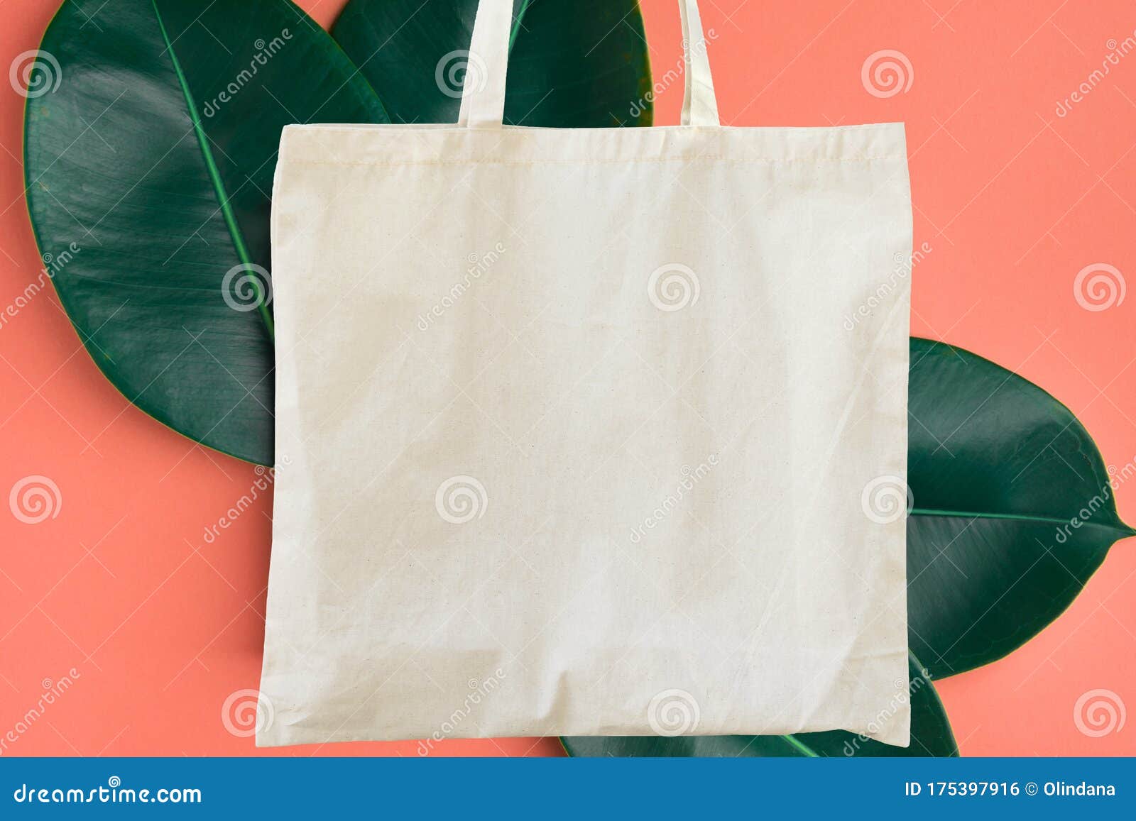blank cotton shite shopper tote bag on pink background with green leaves. mock up template for product branding plastic free