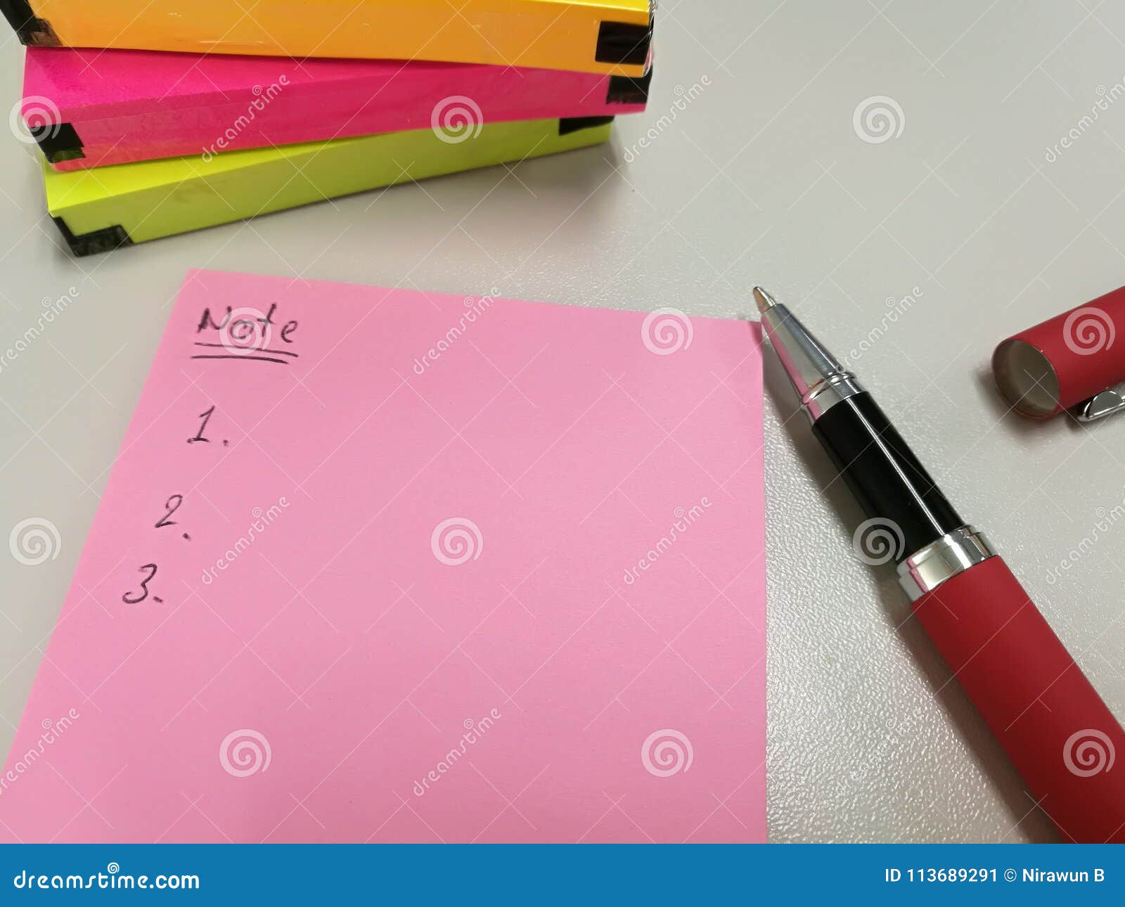blank pink paper note. put near pen and pack of colorful papernote