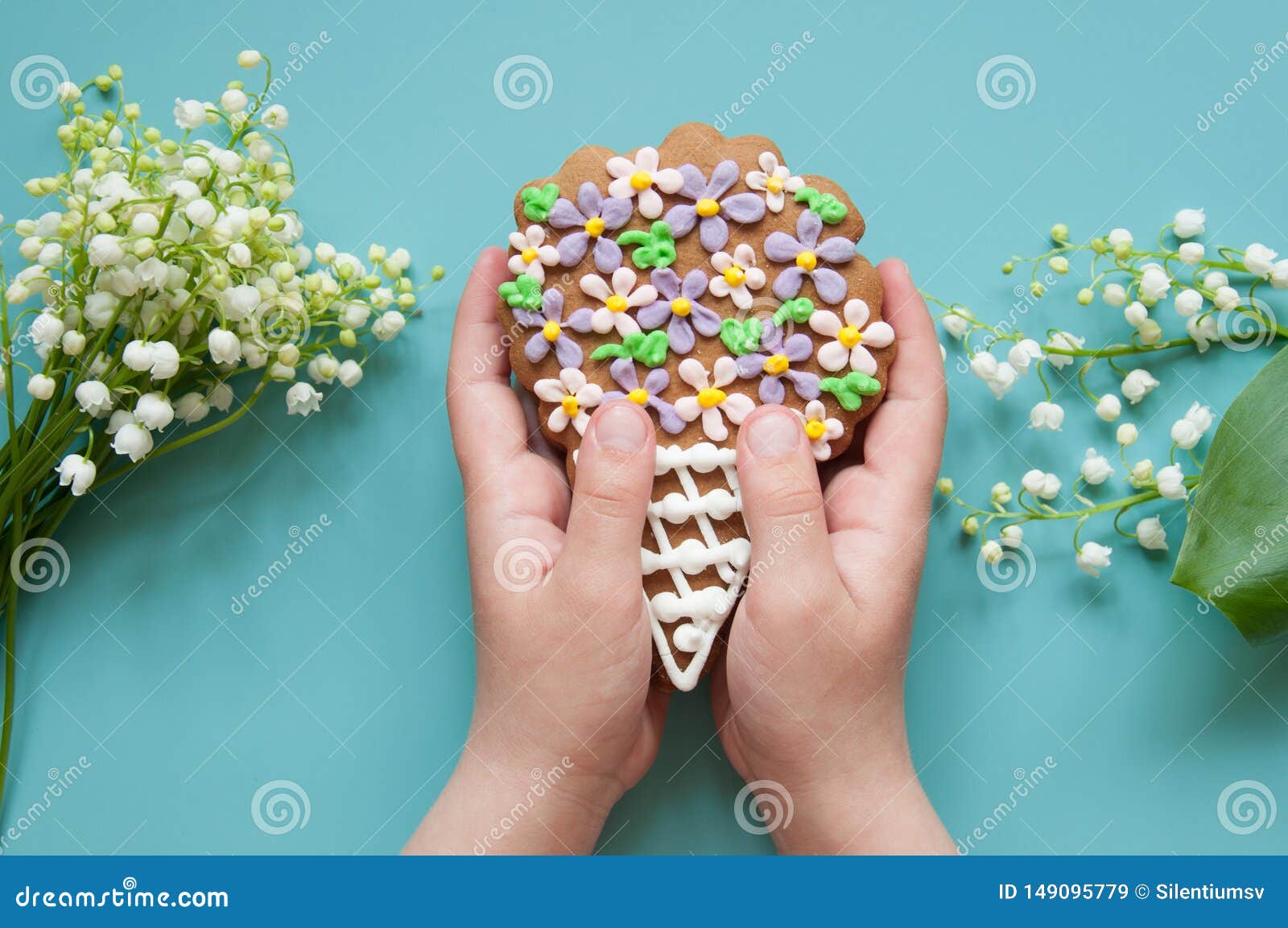 Blauer mit Blumenhintergrund mit frischen Blumen Frühlingsgrußkarte für Muttertag, alles Gute zum Geburtstag, Ostern Ein Blumenstrau? der Lilie des Tales Die Hände der Kinder halten ein Geschenk, Lebkuchenblumenstrauß, Plätzchen