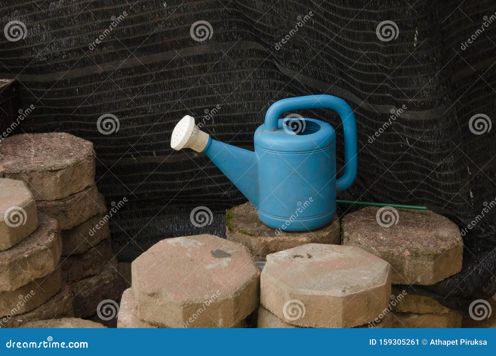 Blauwe waterkuip met een afneembare sprinklerkop. Blauwe waterkering met witte verwijderbare sprinklerkop op betonblokken met zwarte achtergrond