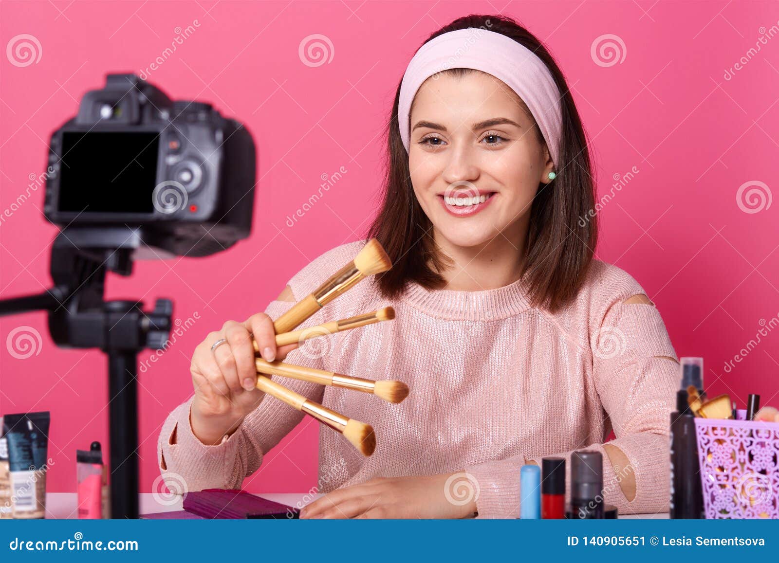 blogging, modern technology and people concept. happy smiling woman beauty video blogger holds brushes for makeup while recording