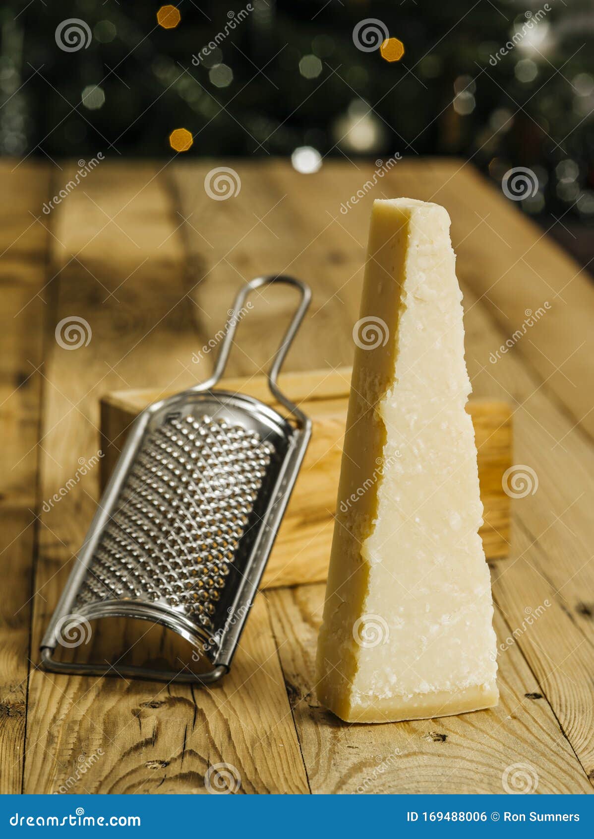 Blok sera i krateru parmezanu. Zdjęcie bloku sera parmezana na drewnianym stole z grater w tle