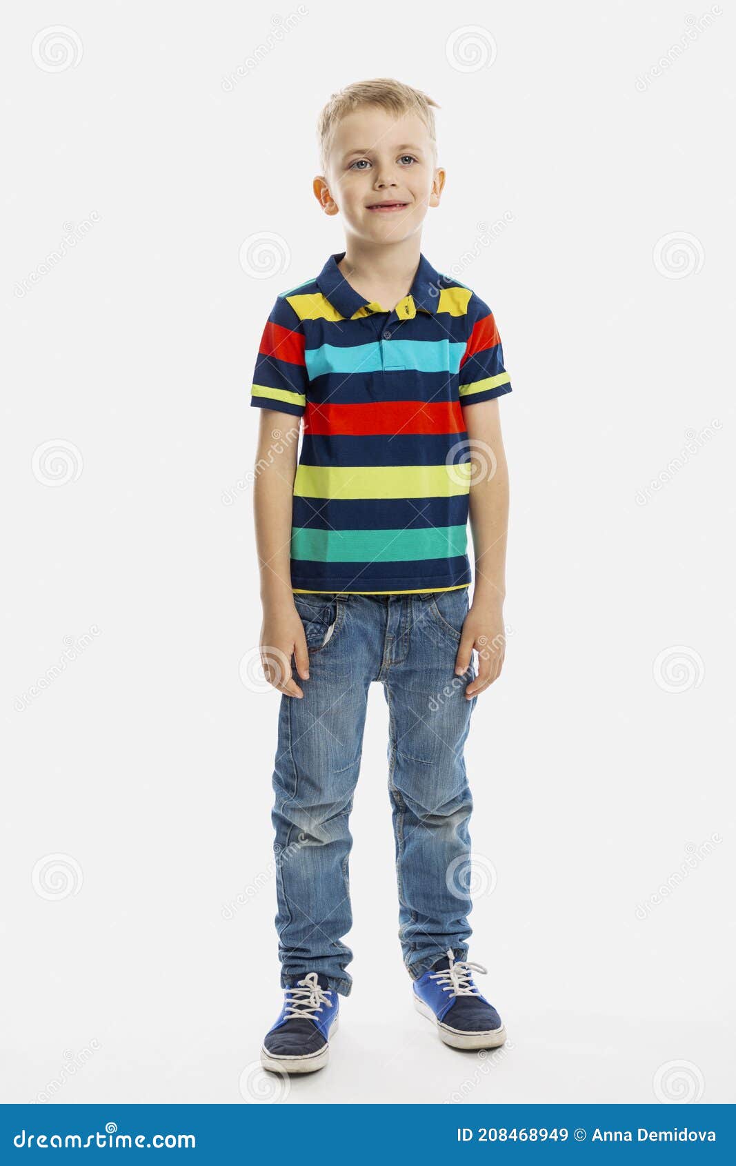 A Blond Boy in Jeans and a Multicolored T-shirt Stands. White ...