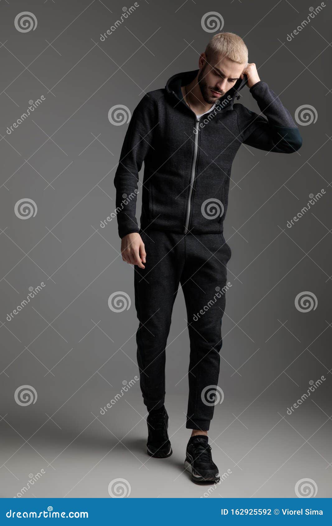 Casual Man Walking while Fixing Hood and Looking Down Stock Photo ...