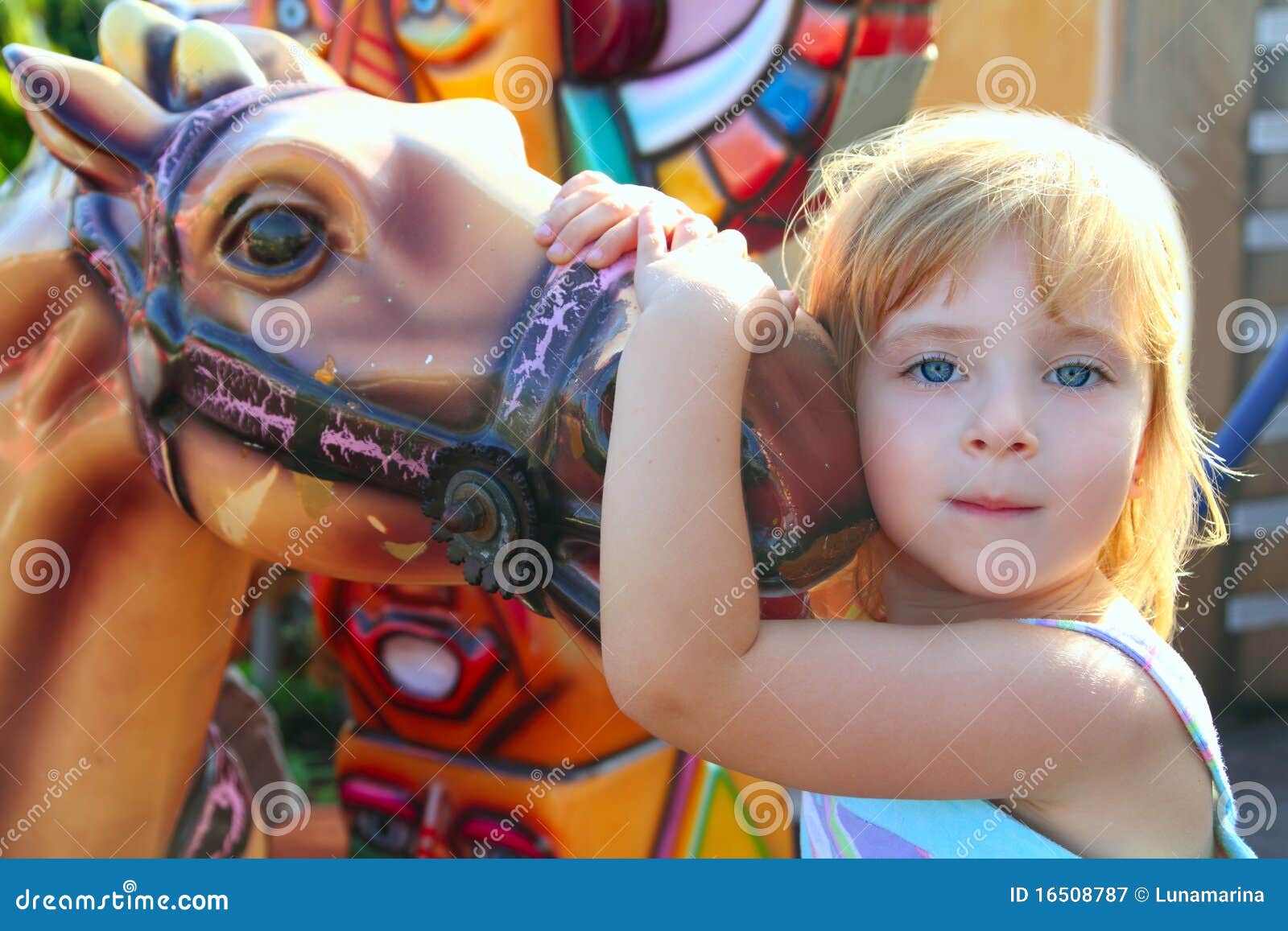 blond girl with fairground horse enjoy in park