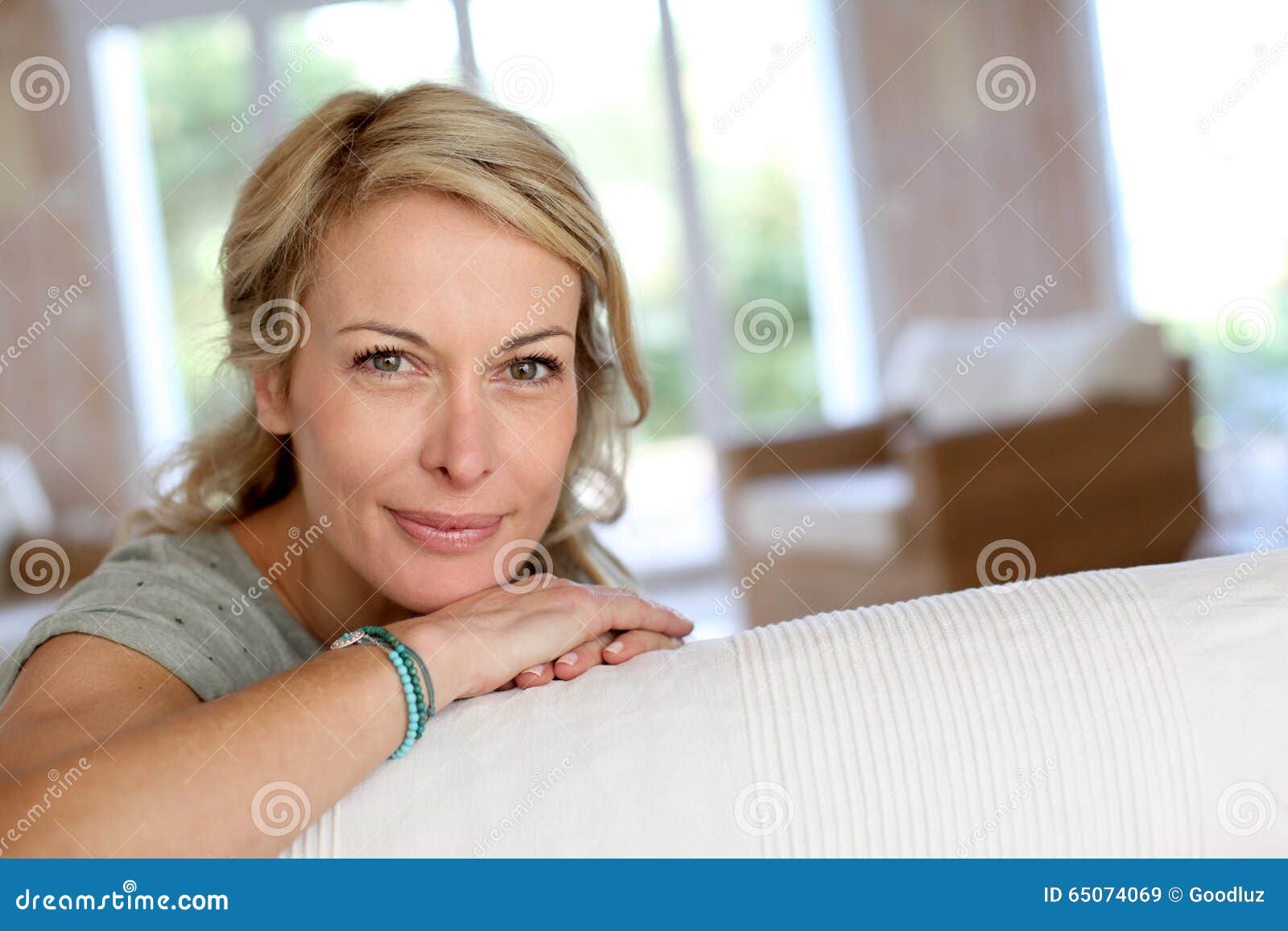 Blond Mature Woman Leaning On Sofa Smiling Stock Image Image Of