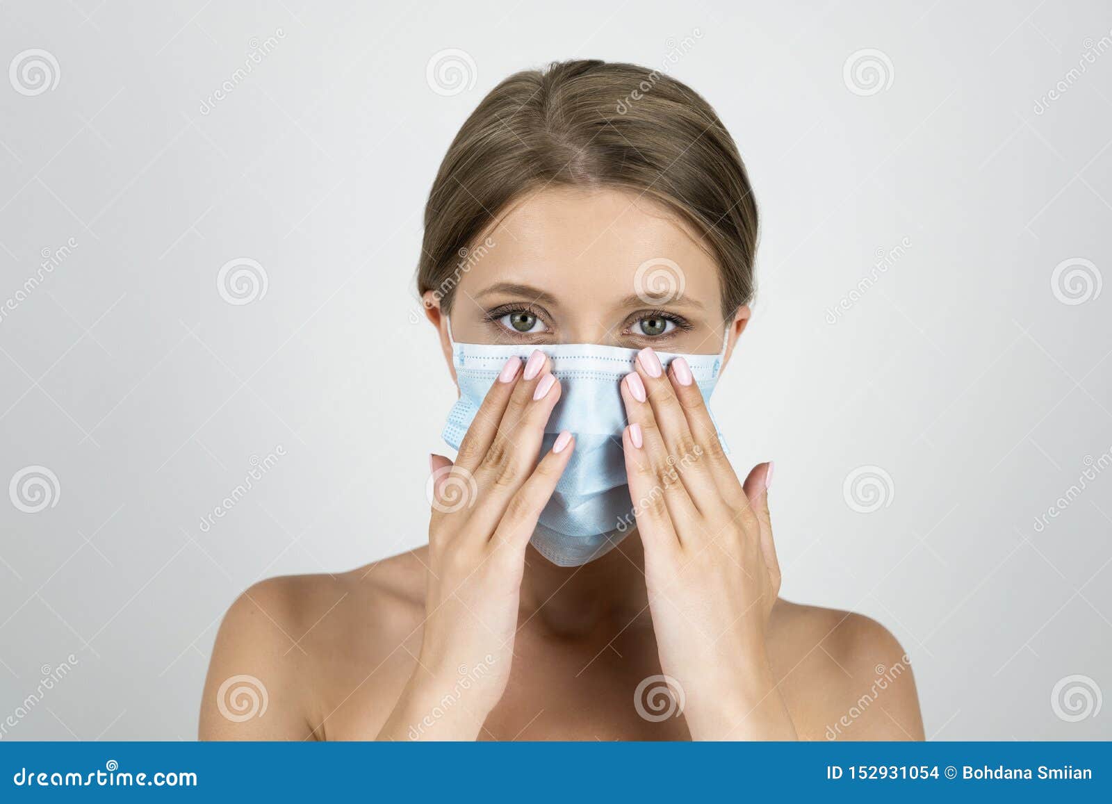 blond young woman wearing medical mask holding hands near her face close up  white background