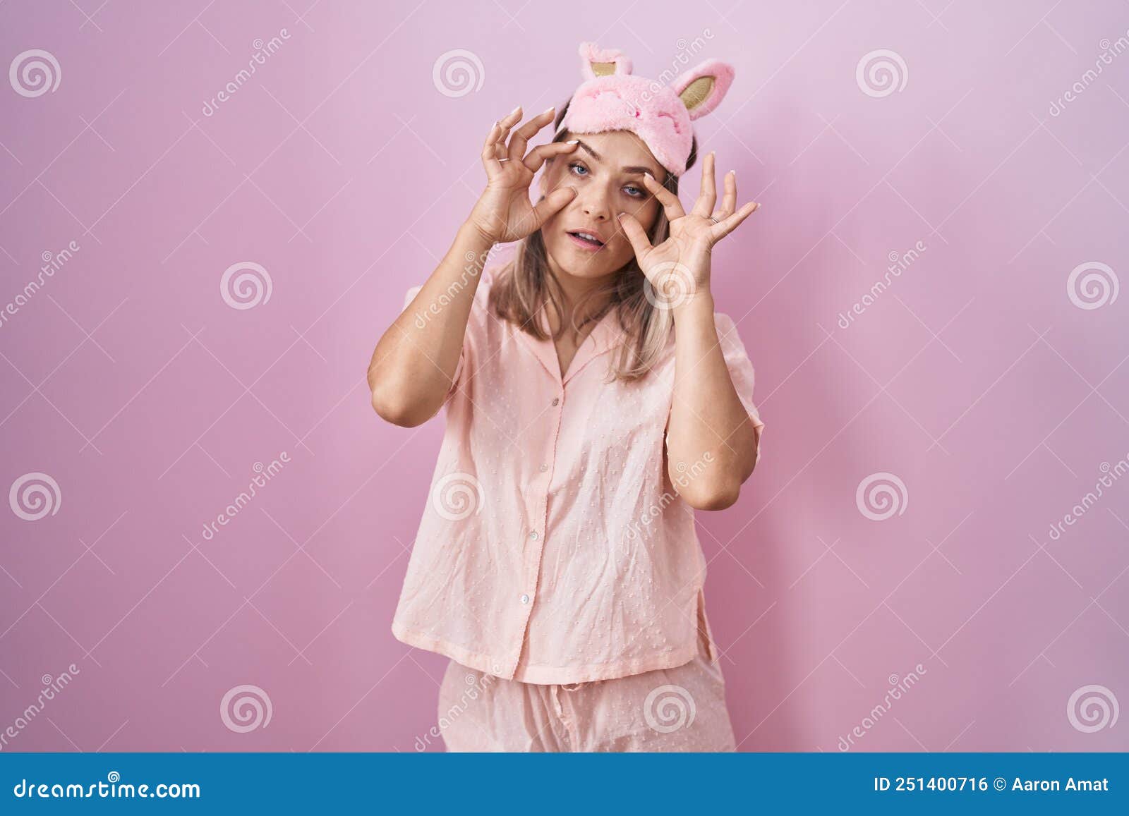 Blonde Caucasian Woman Wearing Sleep Mask And Pajama Trying To Open Eyes With Fingers Sleepy