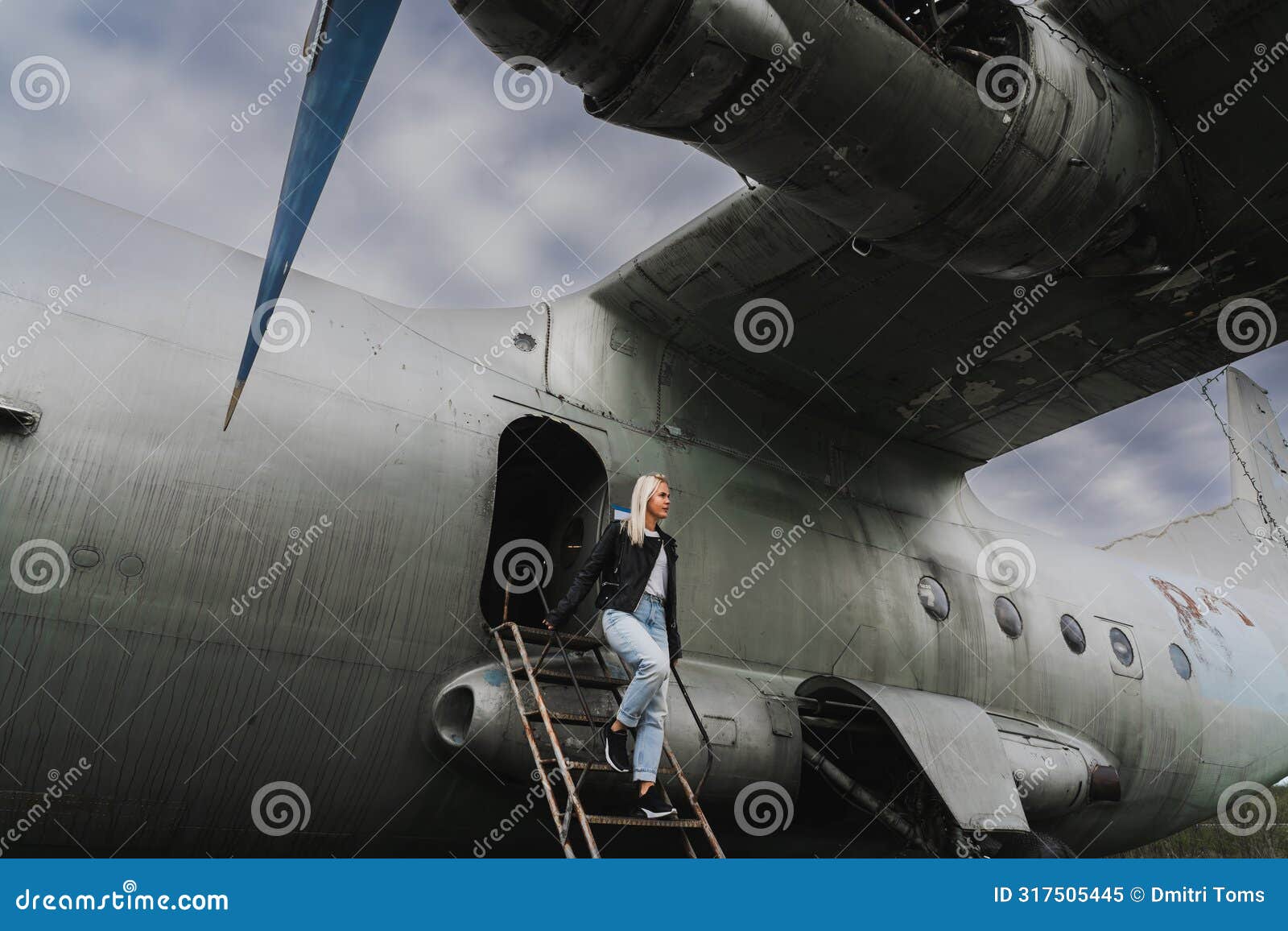 a blonde girl descends the ramp from an old decommissioned soviet military cargo plane an-12