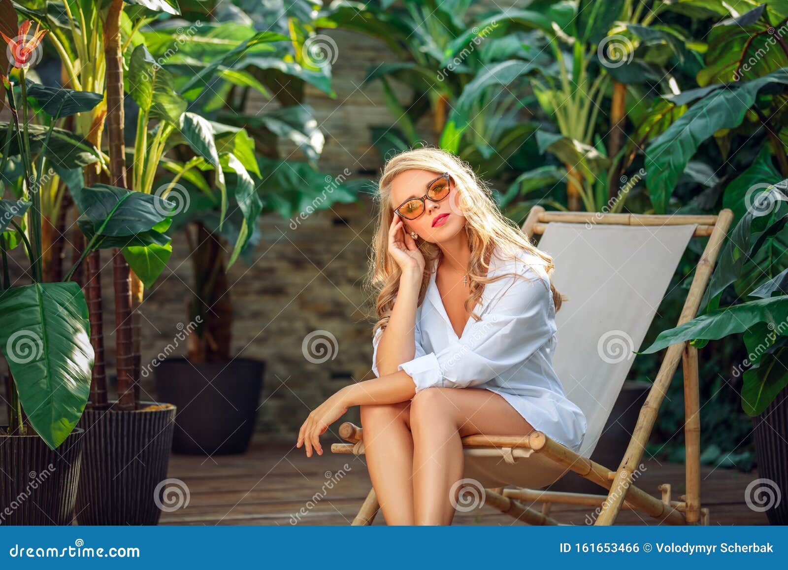 Blonde In Sunglasses On Sun Loungers In A Tropical Hotel On Vacation