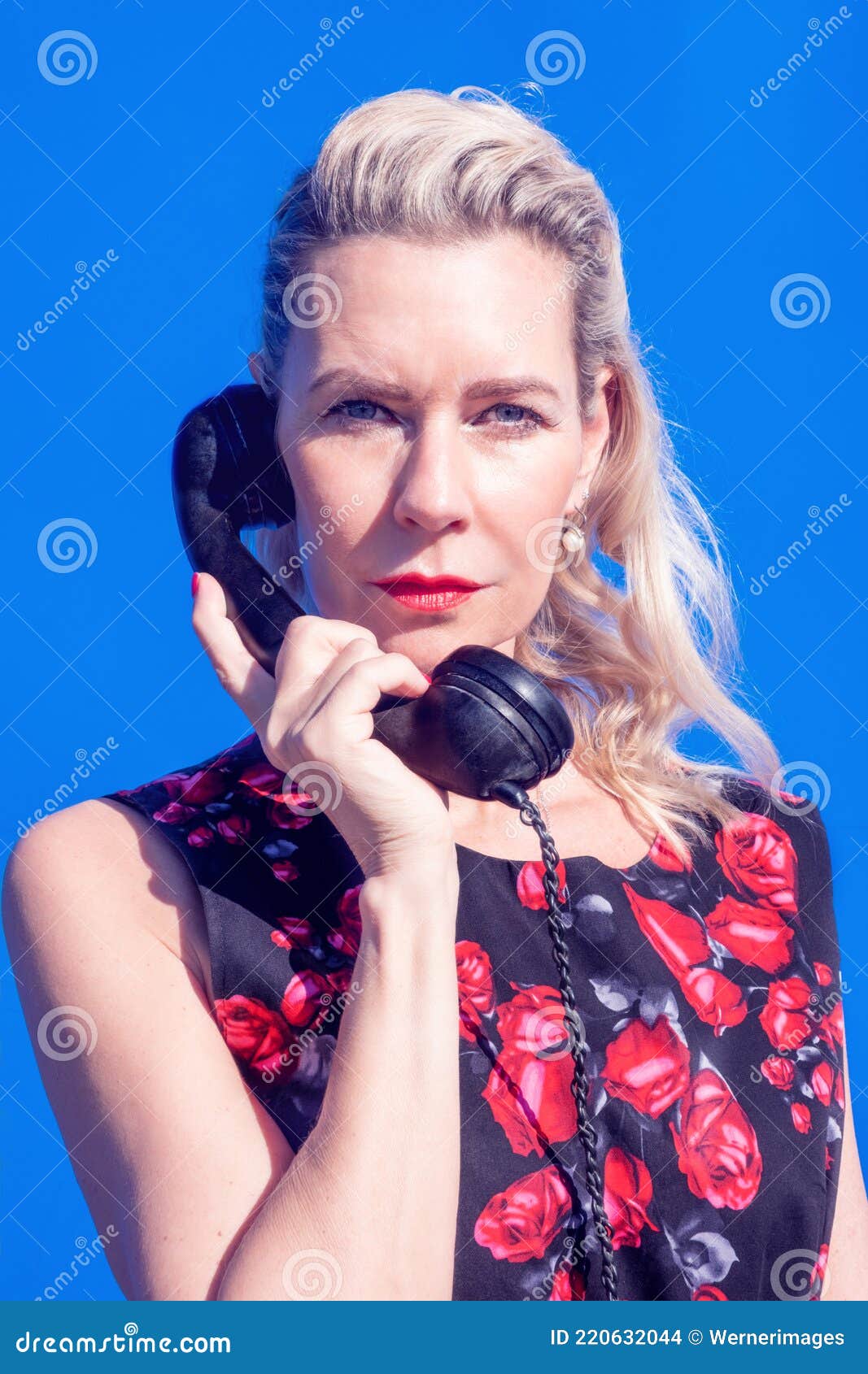 blonde woman in red dress with retro black phone on blue background