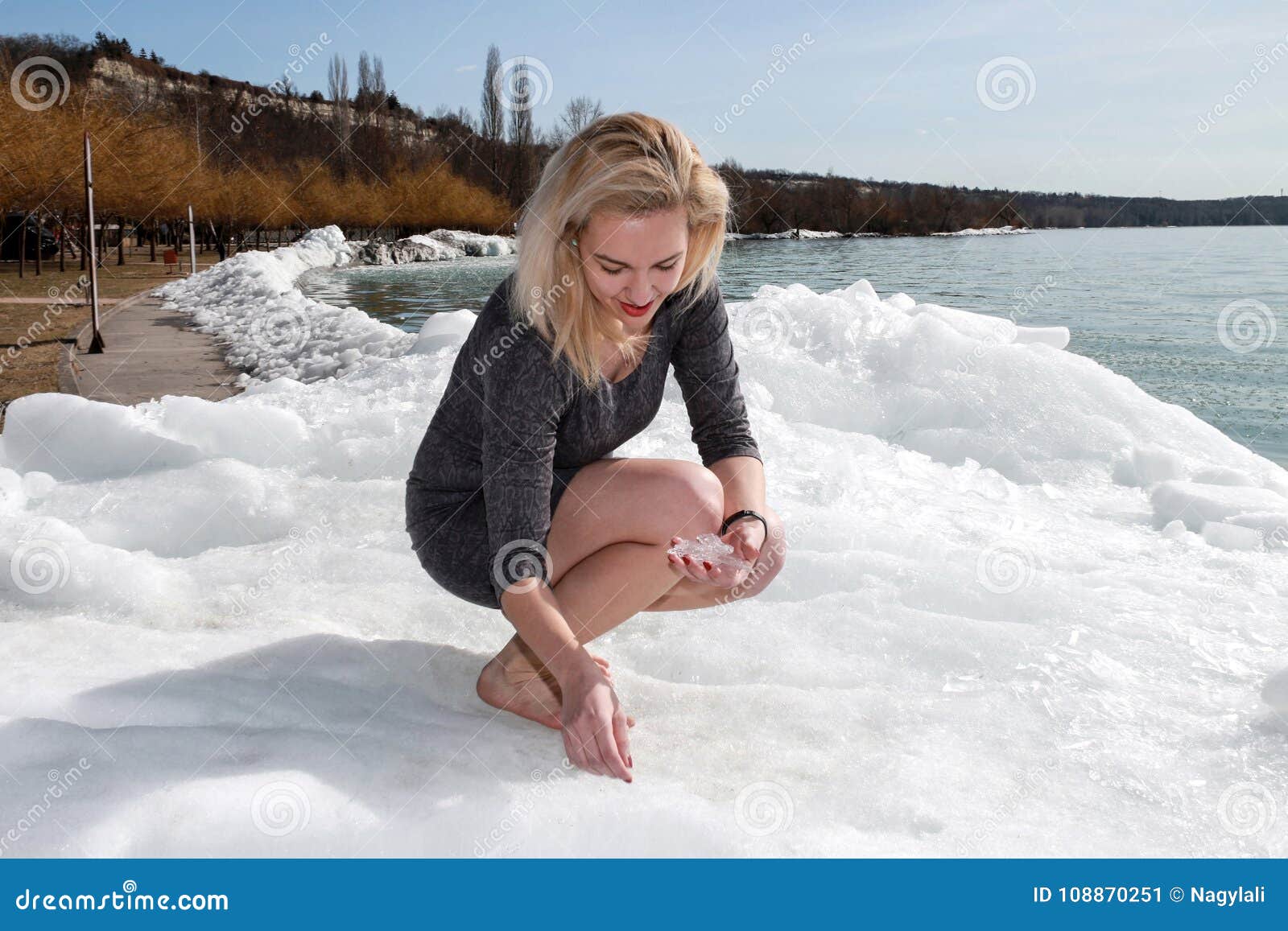 blonde woman is sitting at the frozen coast