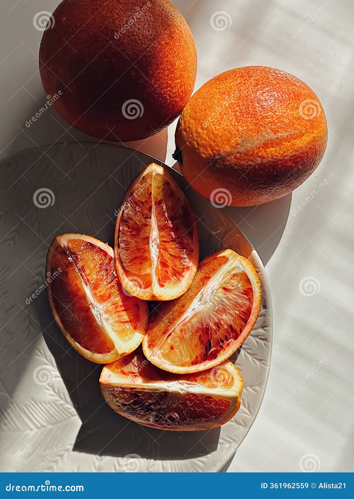 blood oranges against white background with natural sunlight. sanguinello, tarocco