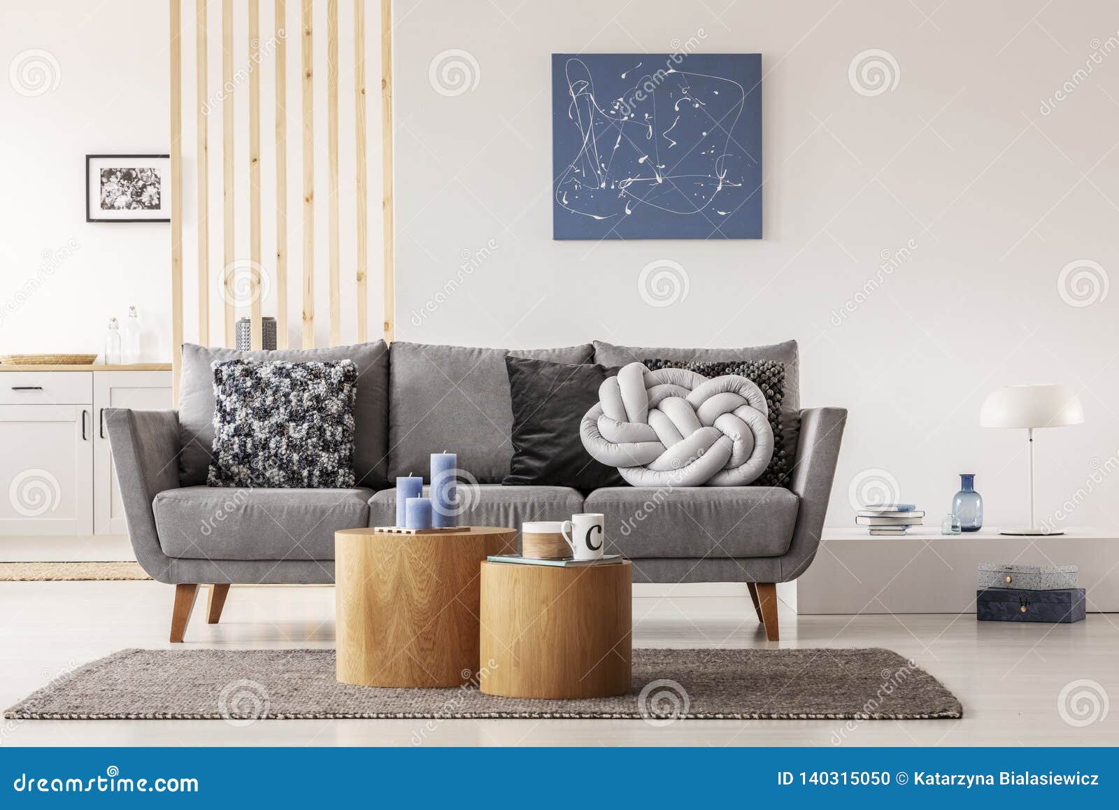 blue abstract painting on white wall of contemporary living room interior with grey settee with pillows