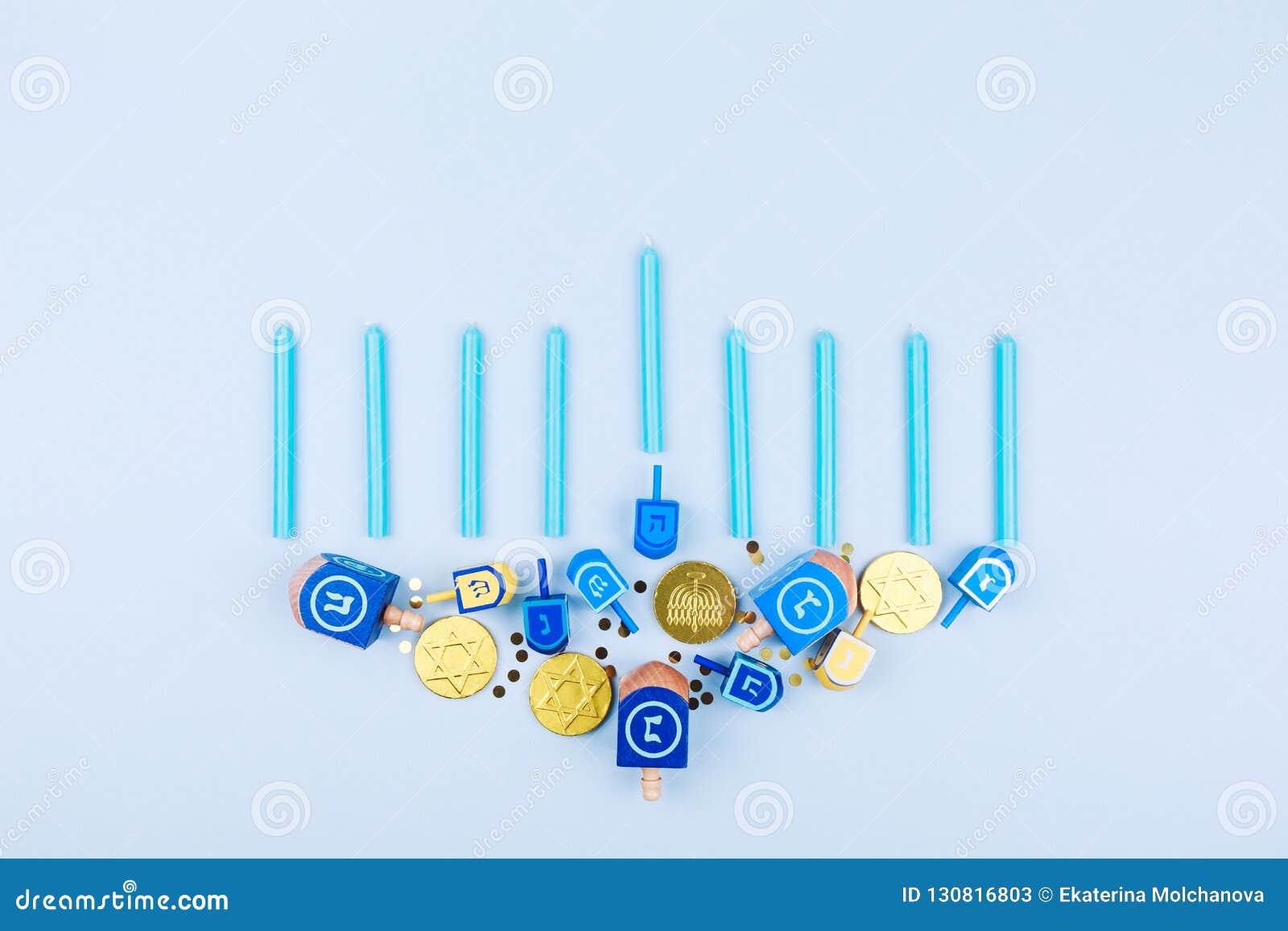 blue background with menora made of dreidels and chocolate coins