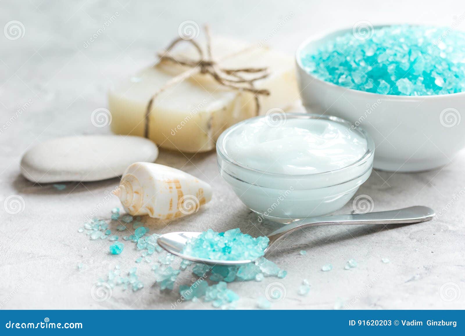 Blue Bath Salt, Body Cream and Shells for Spa on Gray Table Background