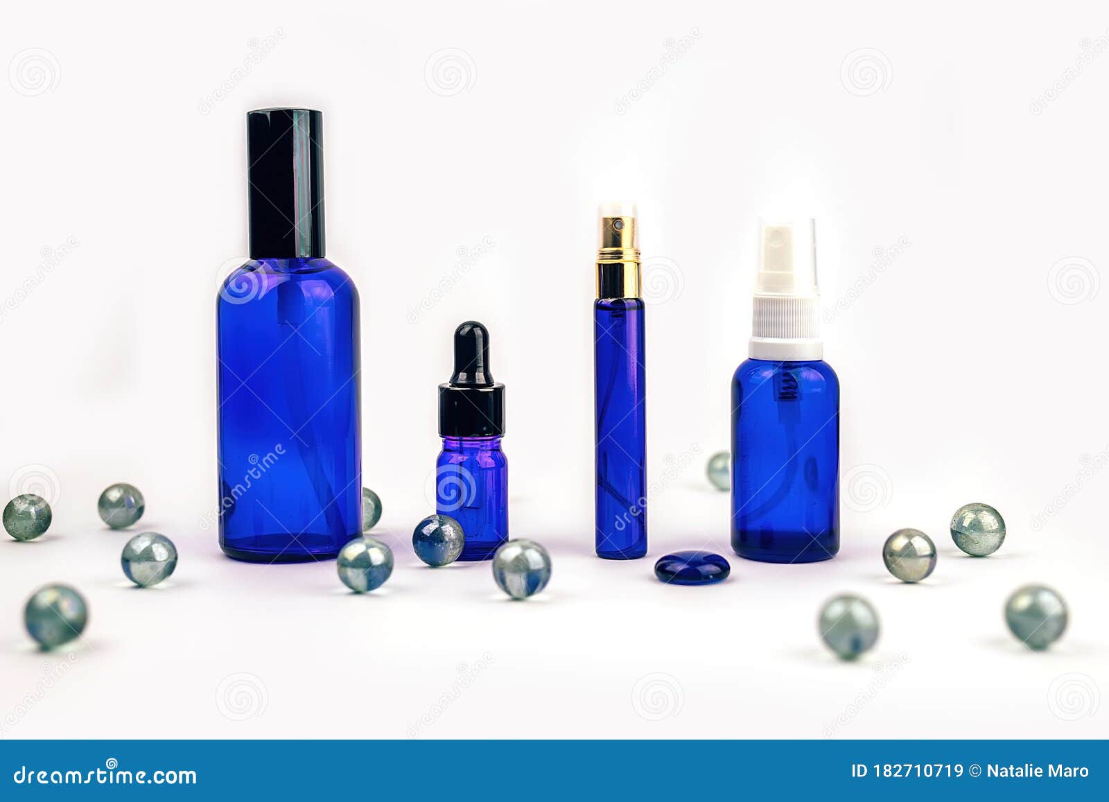 Blue Bottles Of Different Essential Oils With Crystal Balls On White Background Stock Image