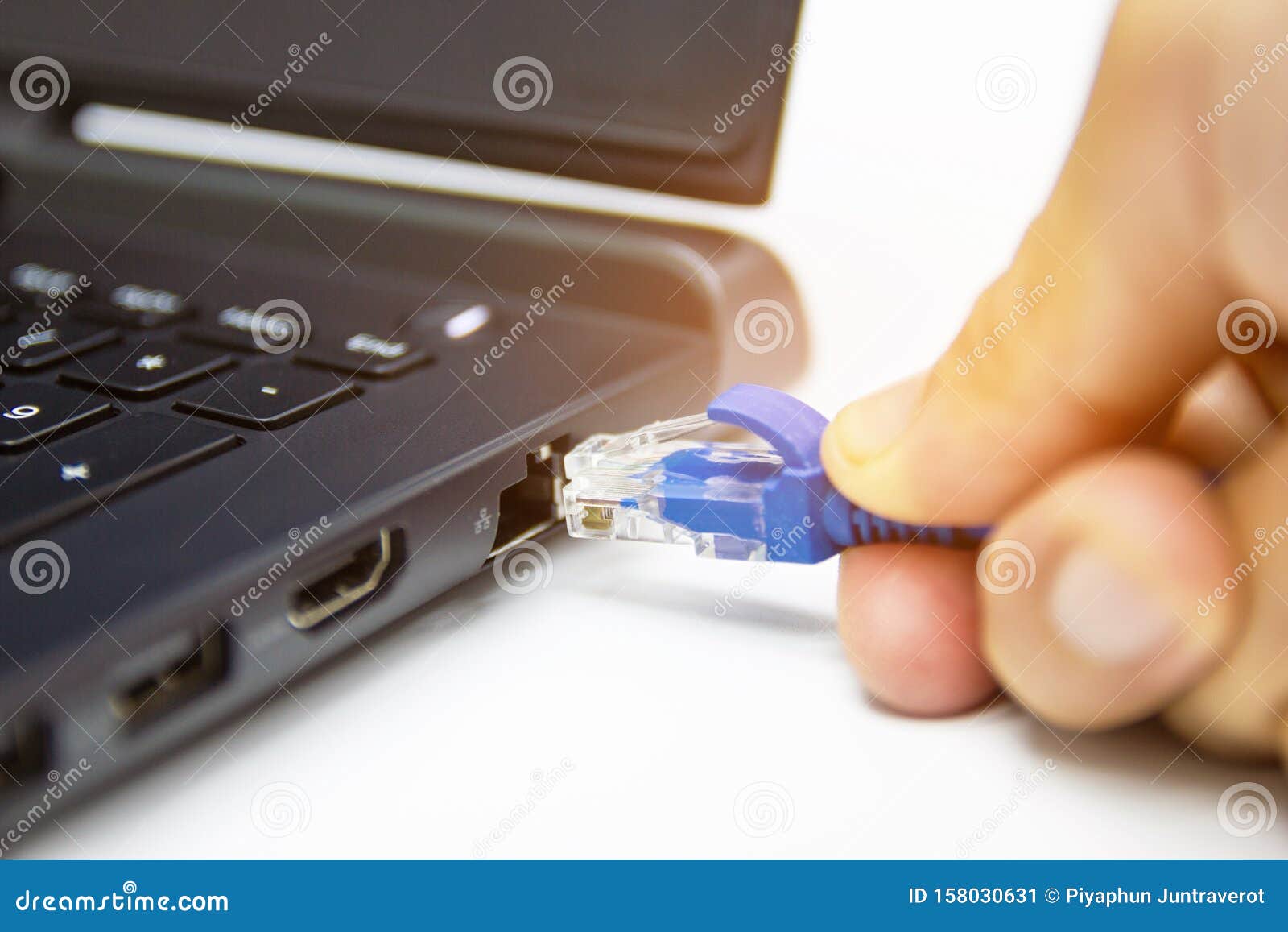 Blue Cable Network Connection To a Lan Port of Laptop Computer on White Table Stock Image