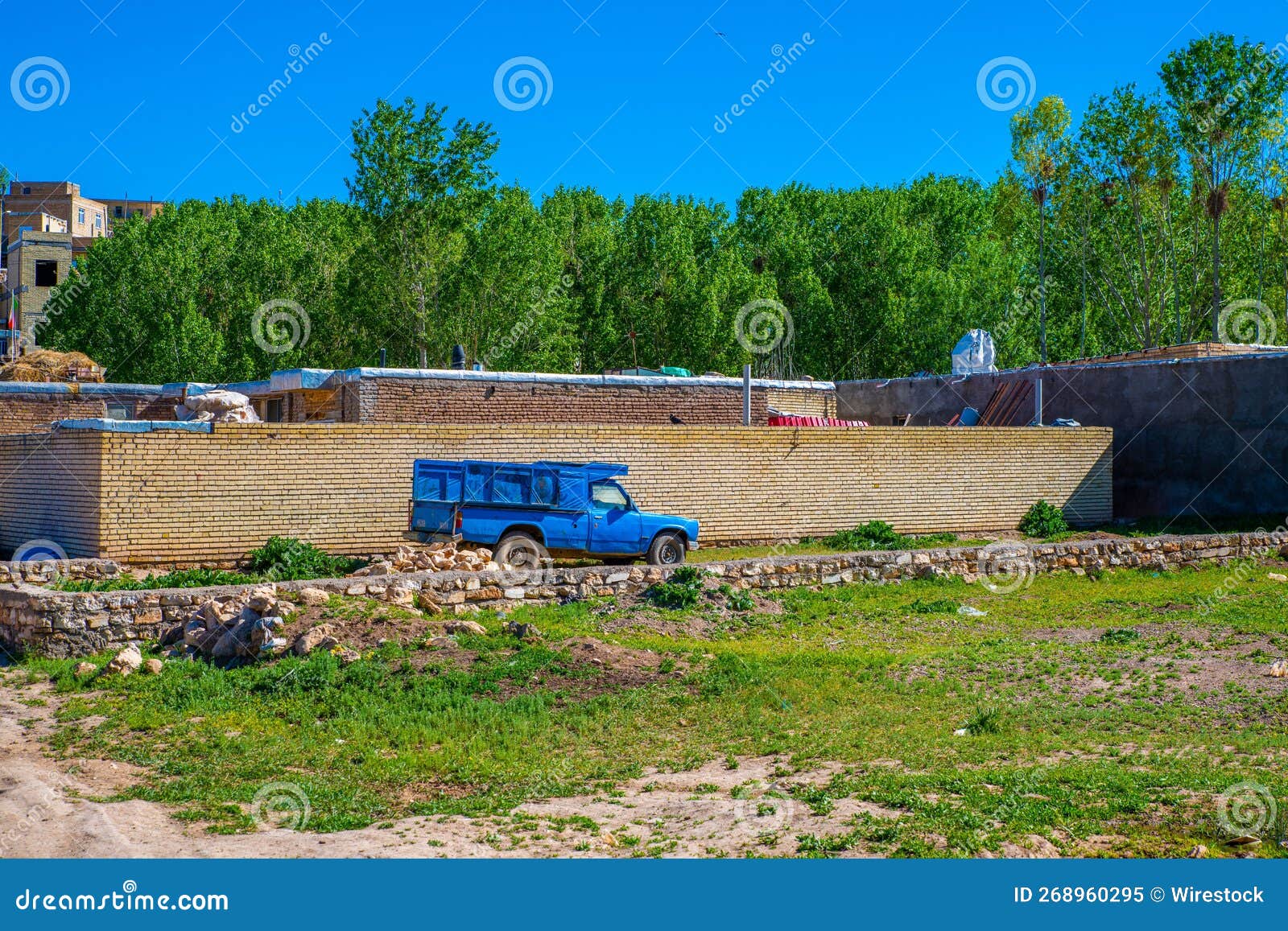 blue car in front of a brick wall in the town of takab in west azerbaijan province, iran.
