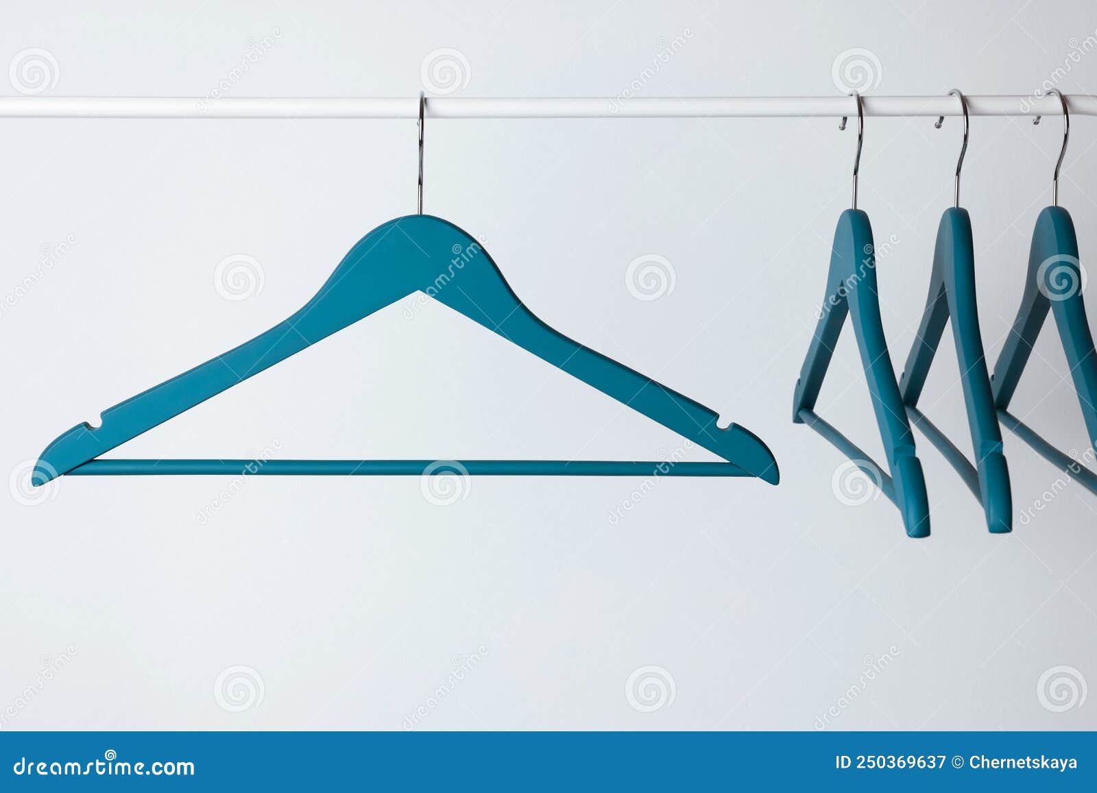 Blue Clothes Hangers on Metal Rail Against Light Background Stock Image