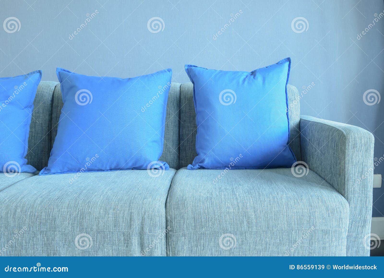 Blue Color Pillows Setting on Light Blue Sofa with Blue Wall Stock