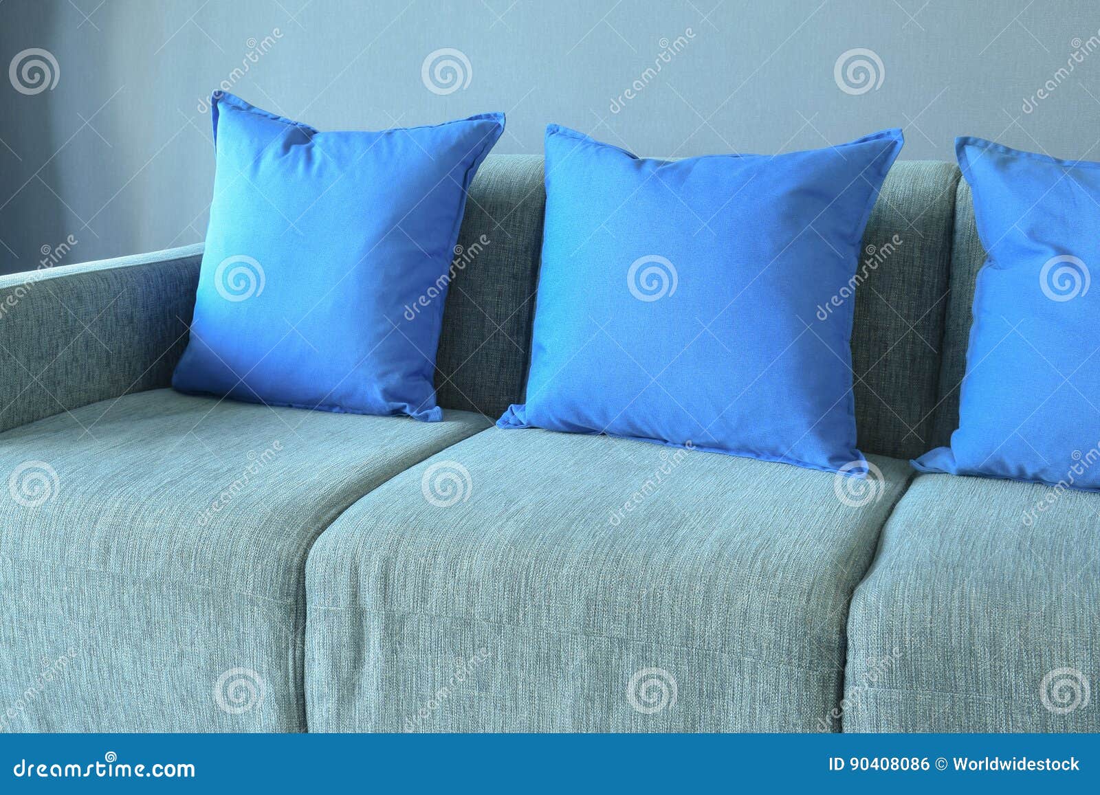 Blue Color Pillows Setting on Light Blue Sofa with Blue Wall Stock