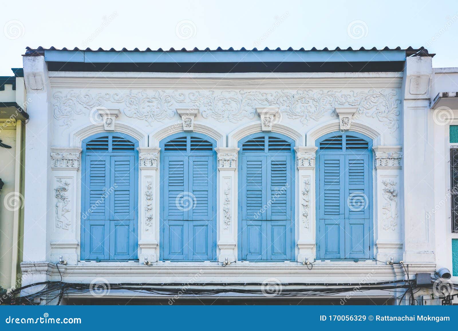 blue color wooden arched window on white cement wall in chino portuguese style at phuket old town, thailand