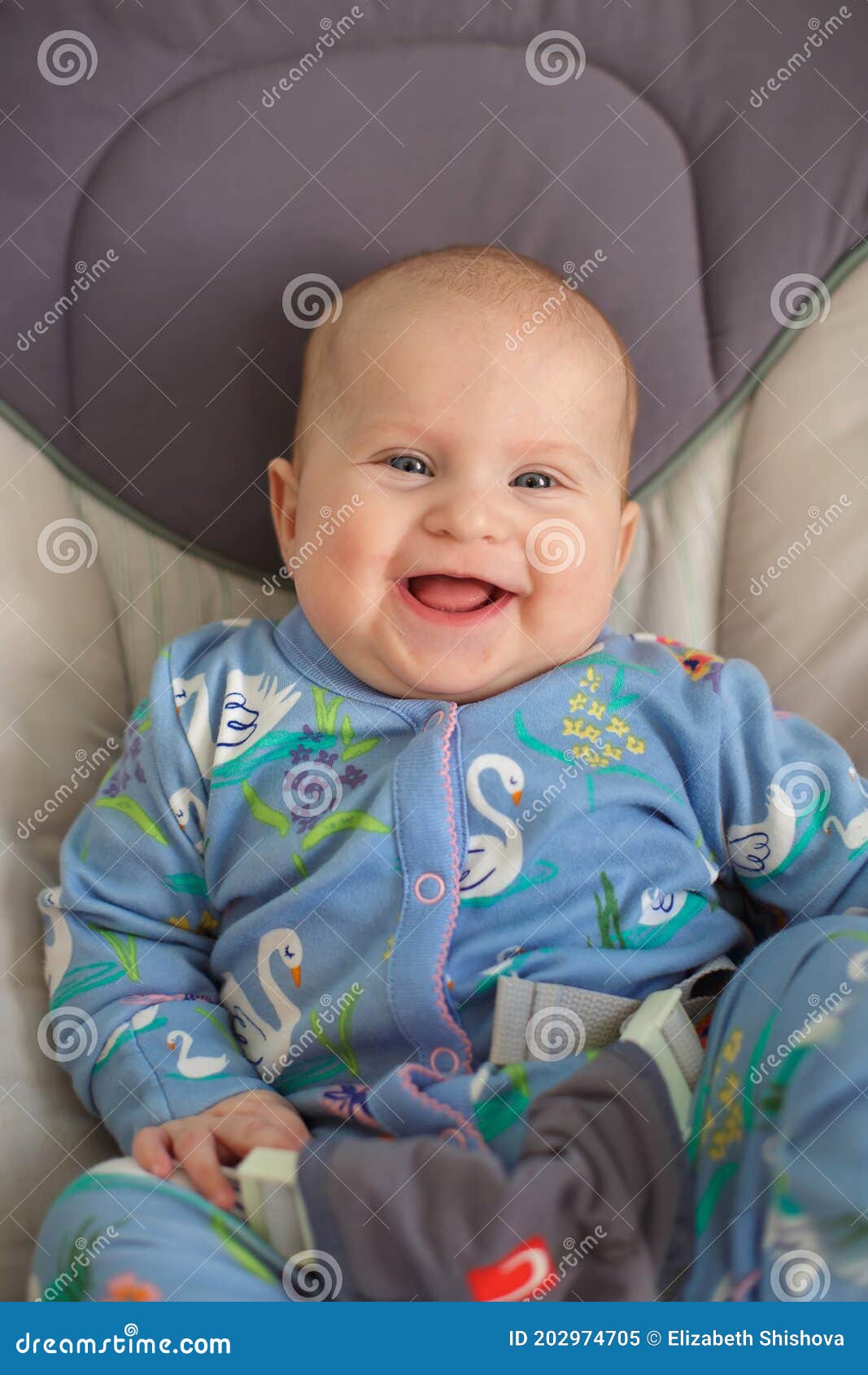 The Blue-eyed Caucasian Baby in Blue Jumpsuit Lies in a Chair and ...