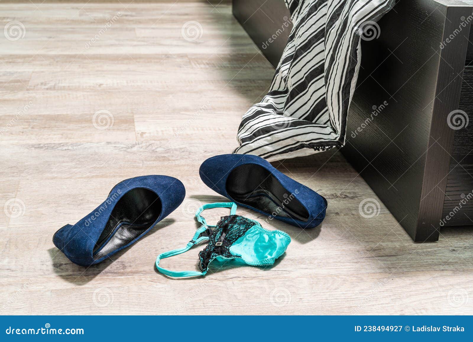 Blue High-heeled Shoes, Green-black Lace Thong Panties and a Condom on the Wooden Floor by the Bed Stock Image image