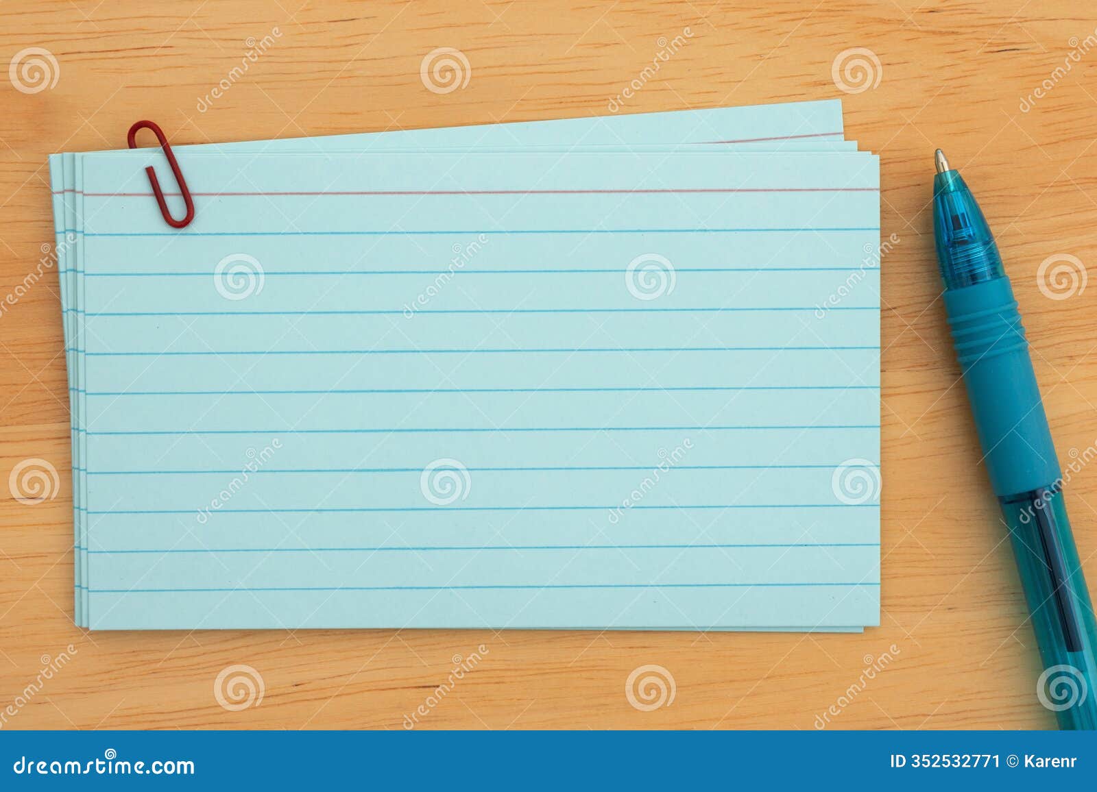 blue index cards with paperclip and pen on wooden desk