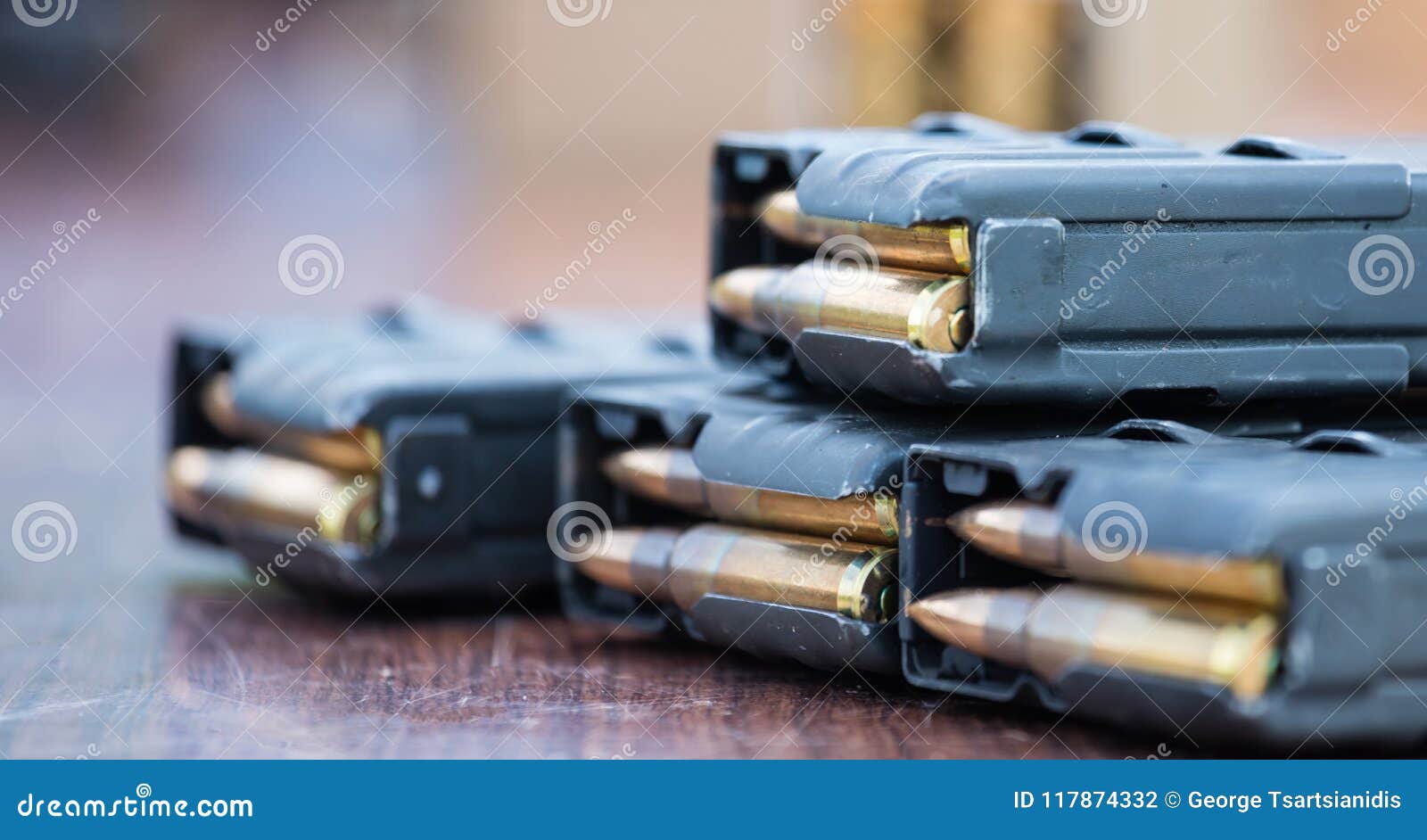 magazines with bullets of firearm putted on wooden table. close up view, blurred background.