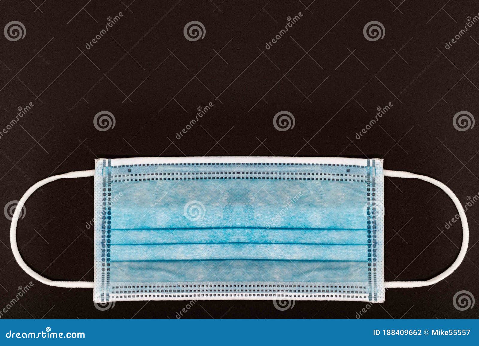 blue medical or surgical face mask. virus protection. black background. space for entering text