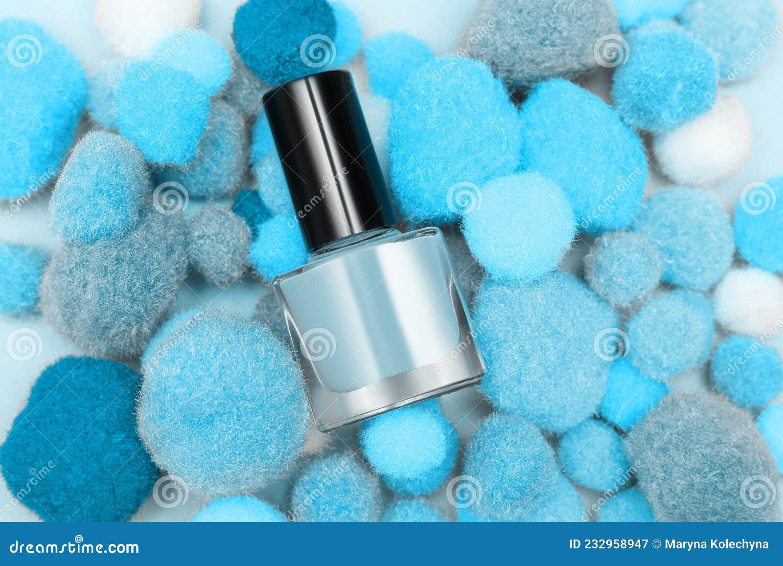 Blue Nail Polish Bottle on Blue Soft Pompons Background. Blue Nail