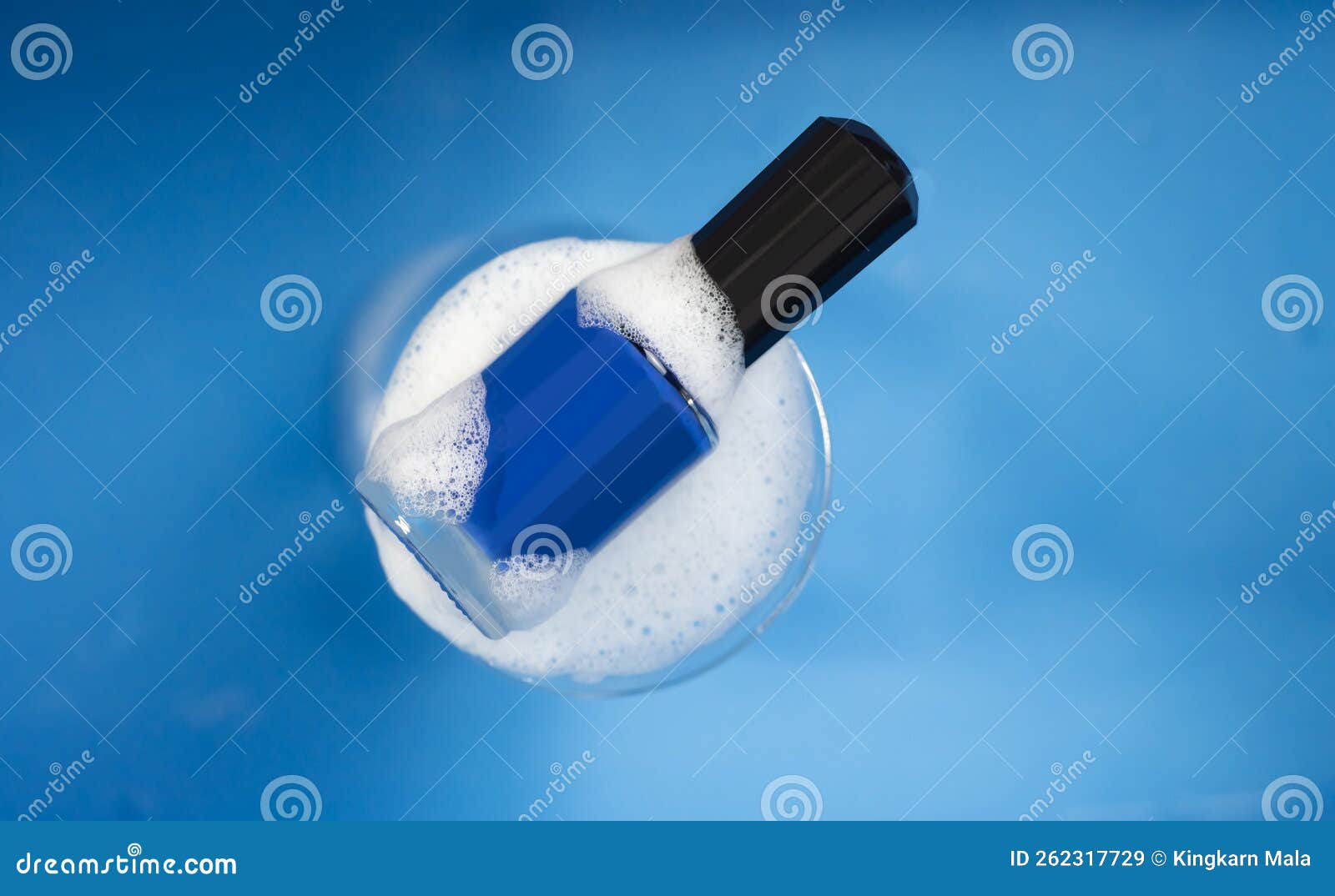The Blue Nail Polish with Soap Bubbles on a Dark Blue Background Stock